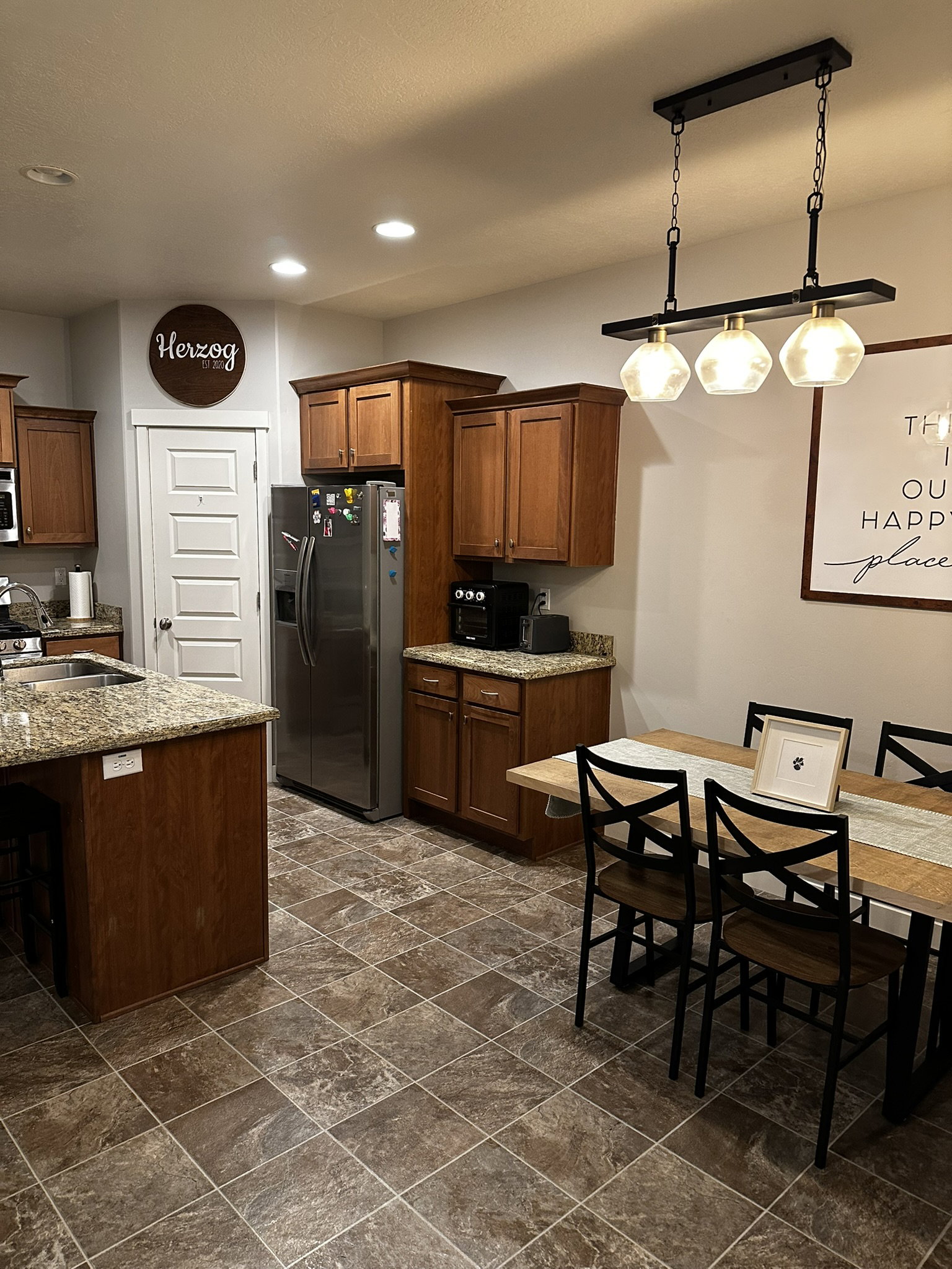 Kitchen and dining area featuring wood-finish cabinetry, granite-style countertops, and tile flooring