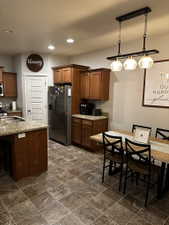 Kitchen and dining area featuring wood-finish cabinetry, granite-style countertops, and tile flooring