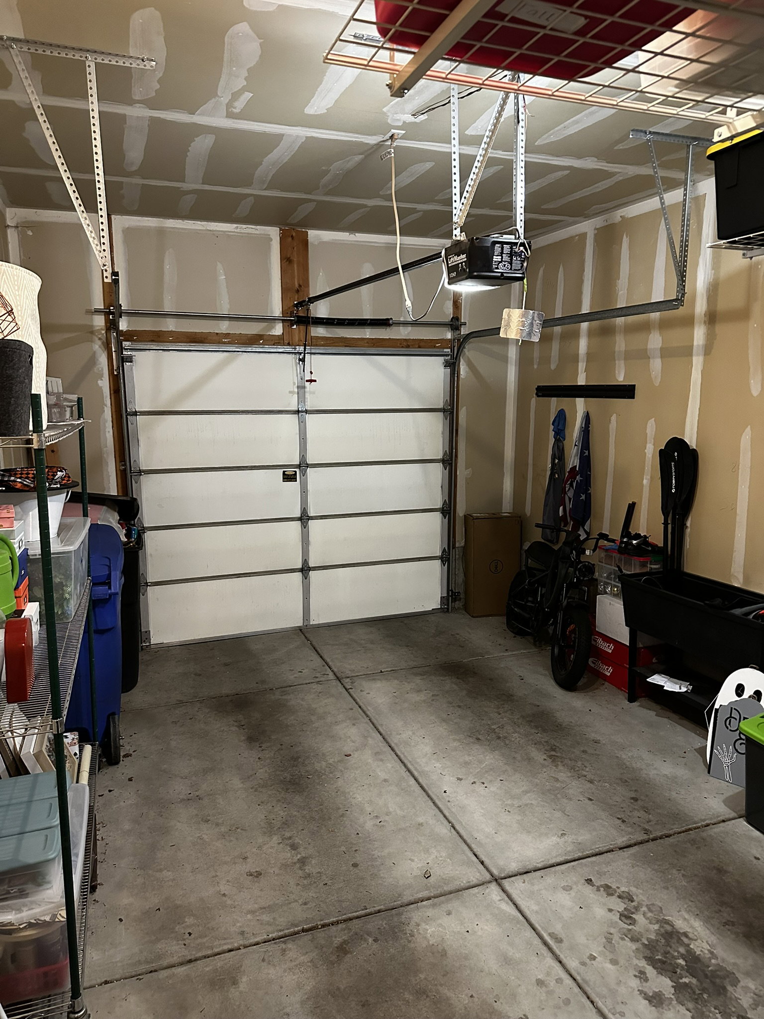 Single-car garage featuring a sectional garage door, concrete flooring, and ceiling-mounted storage racks