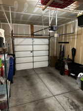 Single-car garage featuring a sectional garage door, concrete flooring, and ceiling-mounted storage racks