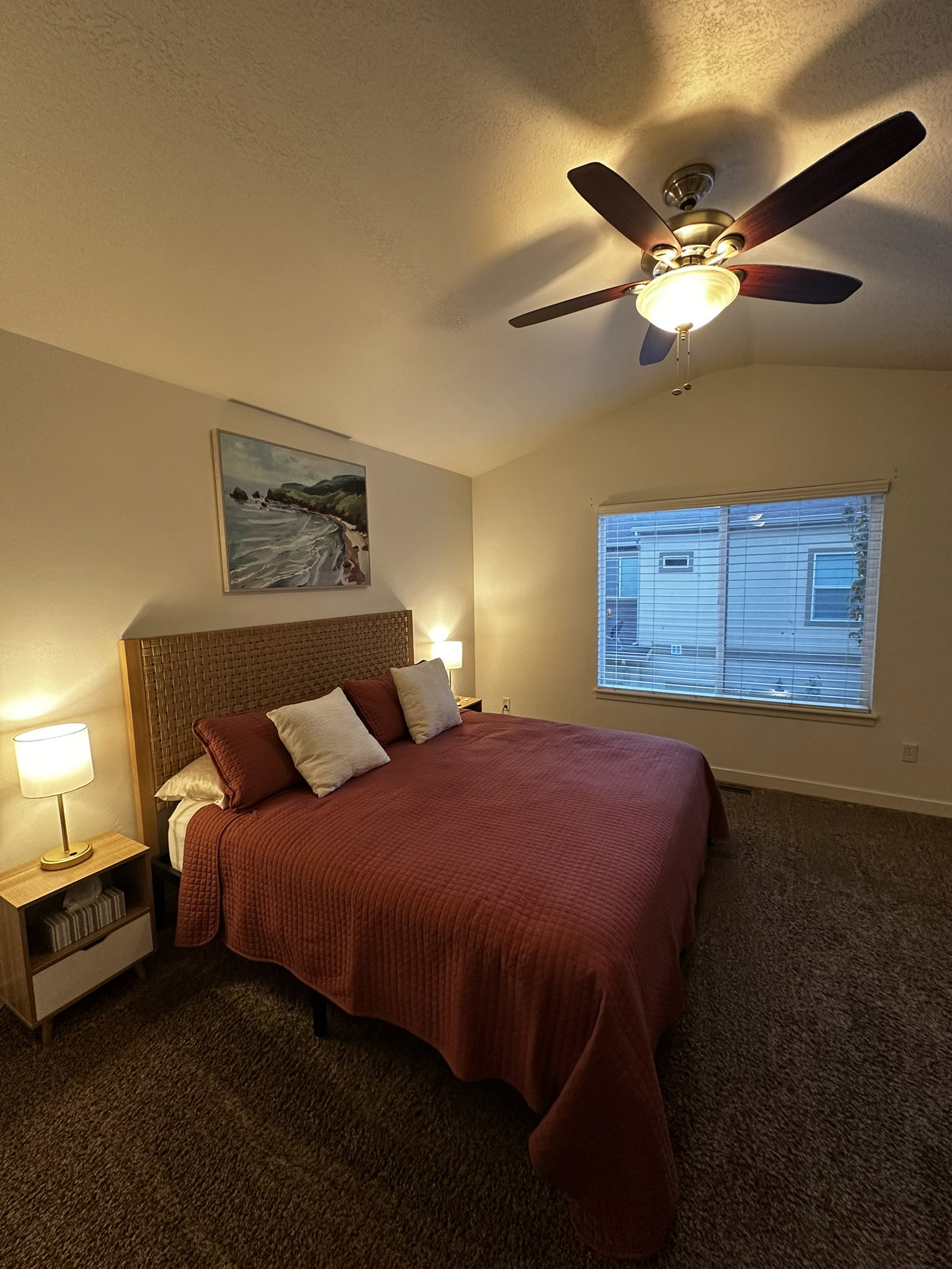 Vaulted ceiling room featuring a ceiling fan with integrated lighting, window with blinds, and carpeted flooring