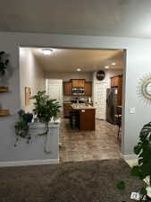 Kitchen featuring wood cabinetry, stainless steel appliances, a center island with bar seating, and tile flooring