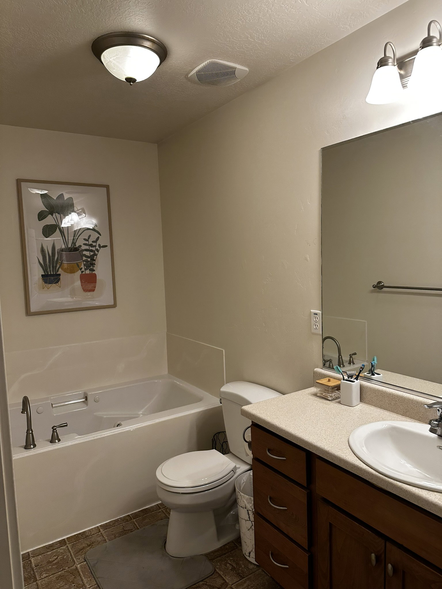 Bathroom featuring a white soaking tub, white toilet, and a vanity with a light-colored countertop