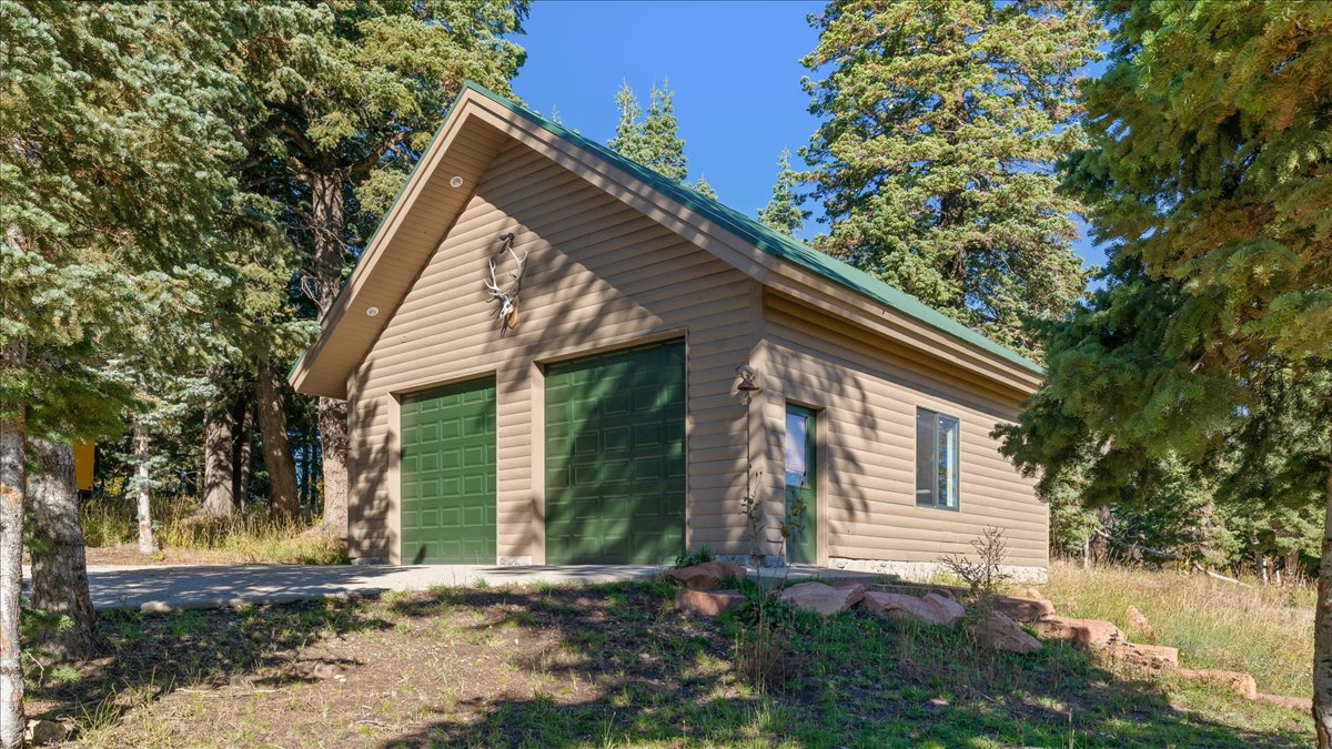 Two-car garage with green doors, beige siding, and a green roof