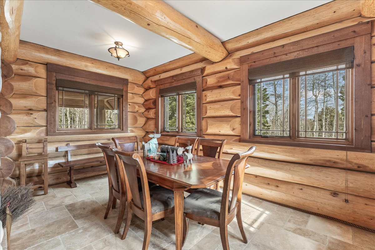 Log cabin interior featuring exposed wood beams, wood paneling, and natural wood window frames