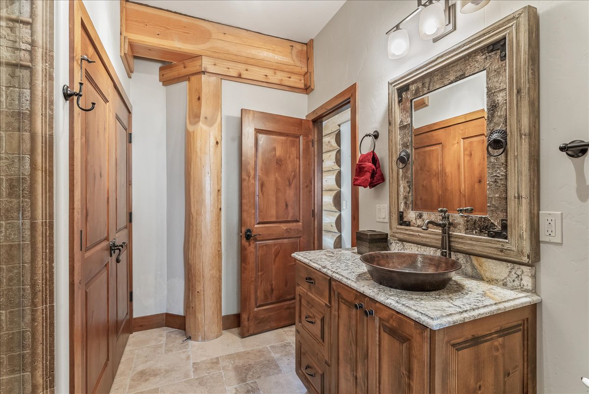 Vanity featuring a copper vessel sink, granite countertop, and wood-finish cabinetry