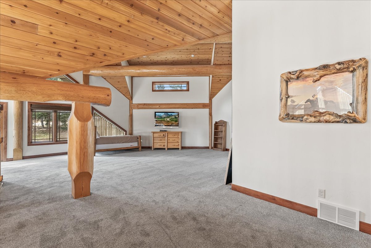 Spacious room featuring substantial wood columns and exposed wood-beam ceiling