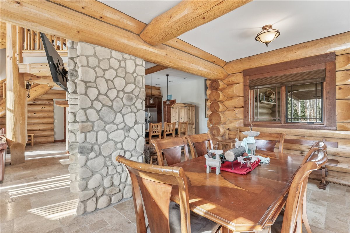 Dining area featuring natural wood log walls and ceiling beams