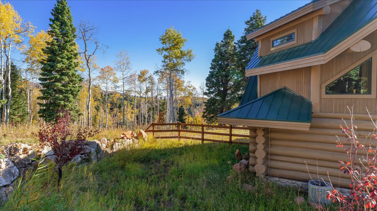 Log cabin exterior featuring a green metal roof, natural wood siding, and prominent triangular windows