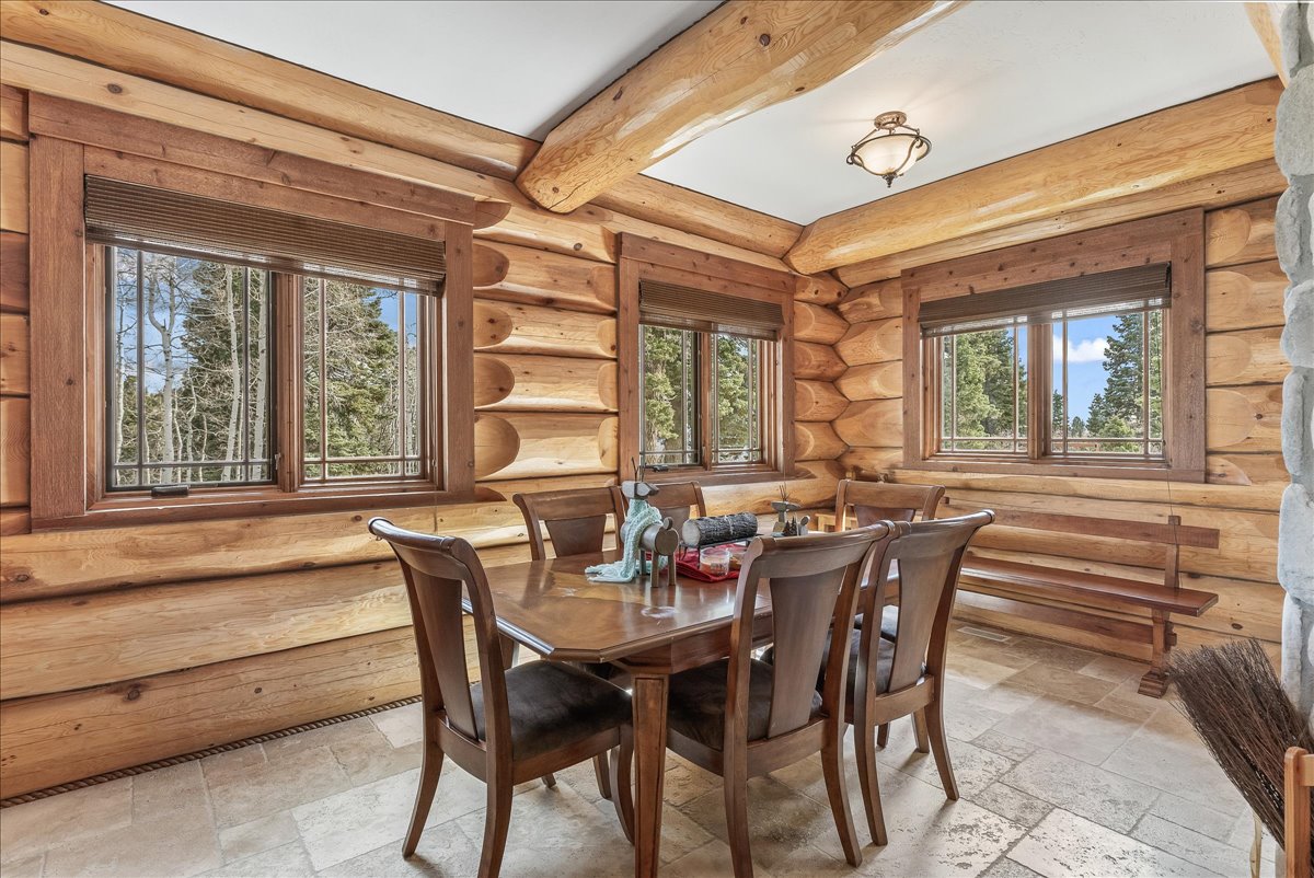 Natural wood log wall construction featuring exposed ceiling beams and a stone-clad pillar