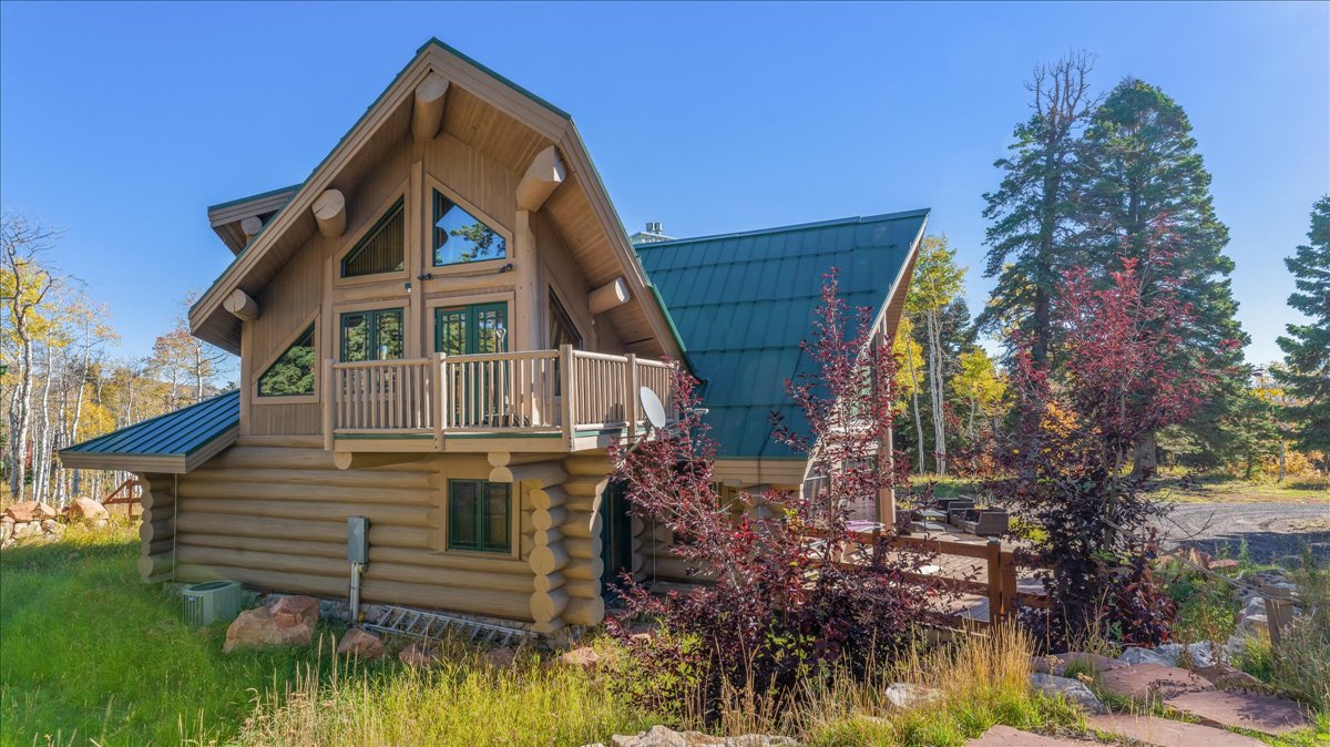 Log cabin exterior featuring a steep-pitch green metal roof