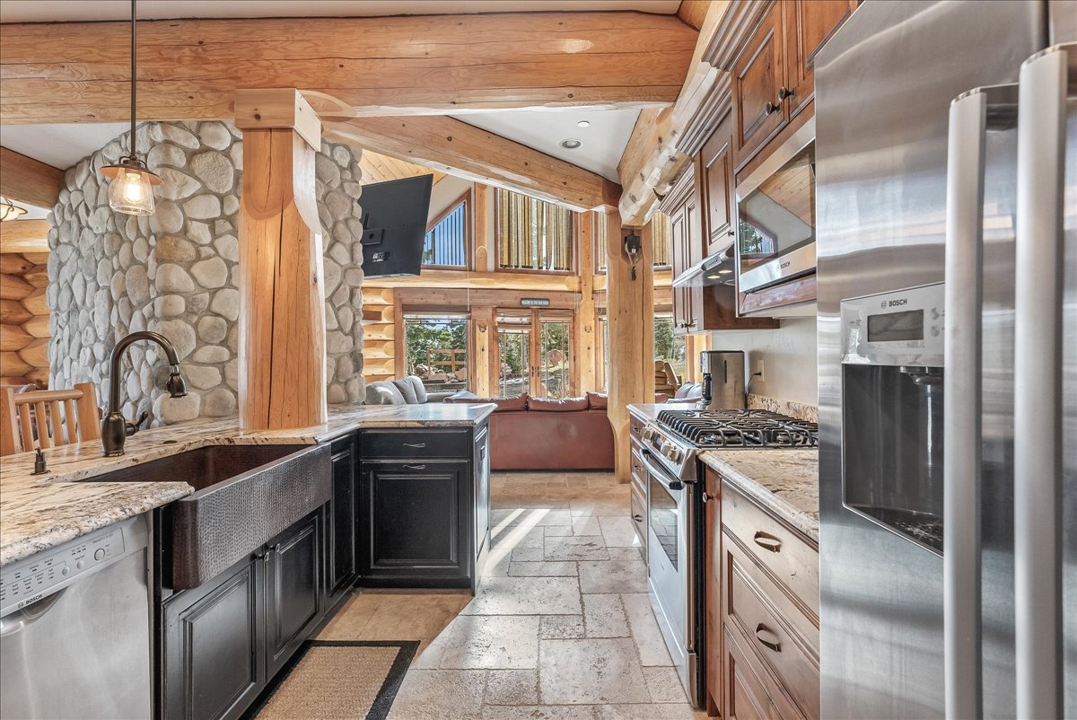 Gourmet kitchen featuring a large farmhouse sink, stainless steel appliances, stone countertops, and extensive custom cabinetry