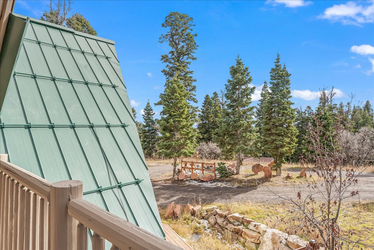 A-frame architecture featuring a green metal roof and wooden balcony railing