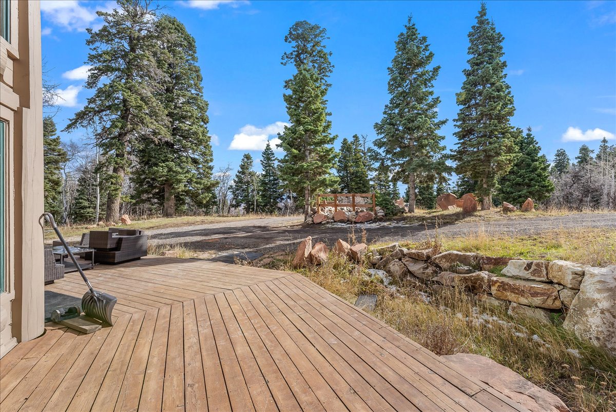 Expansive wood-finish deck with a geometric pattern, surrounded by mature evergreen trees