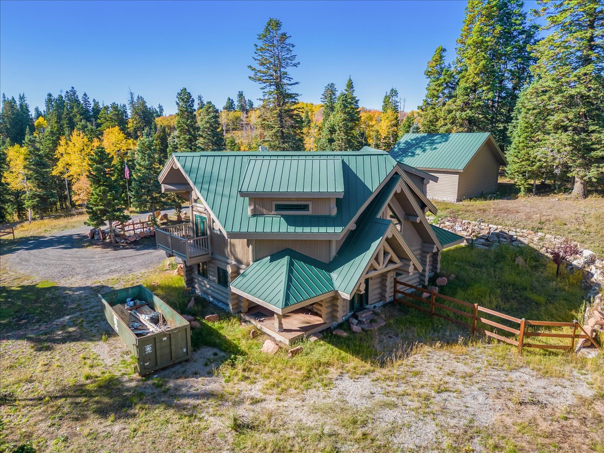 Log cabin style residence featuring a green metal roof, a second-story balcony, and a covered porch entry