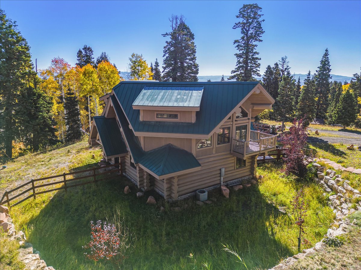 Log home featuring a dark green metal roof and an upper-level balcony