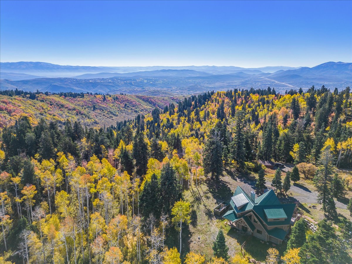 Expansive mountain property featuring a multi-level residence with a deep green metal roof