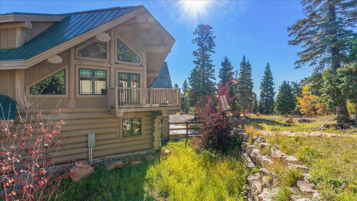 Log-style residence featuring a green metal roof, a second-story balcony, and varied geometric windows