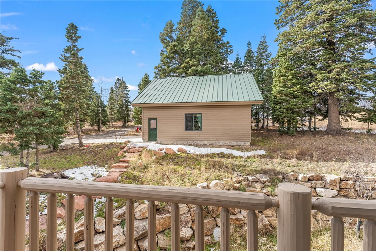 Detached outbuilding with a green metal roof and beige siding