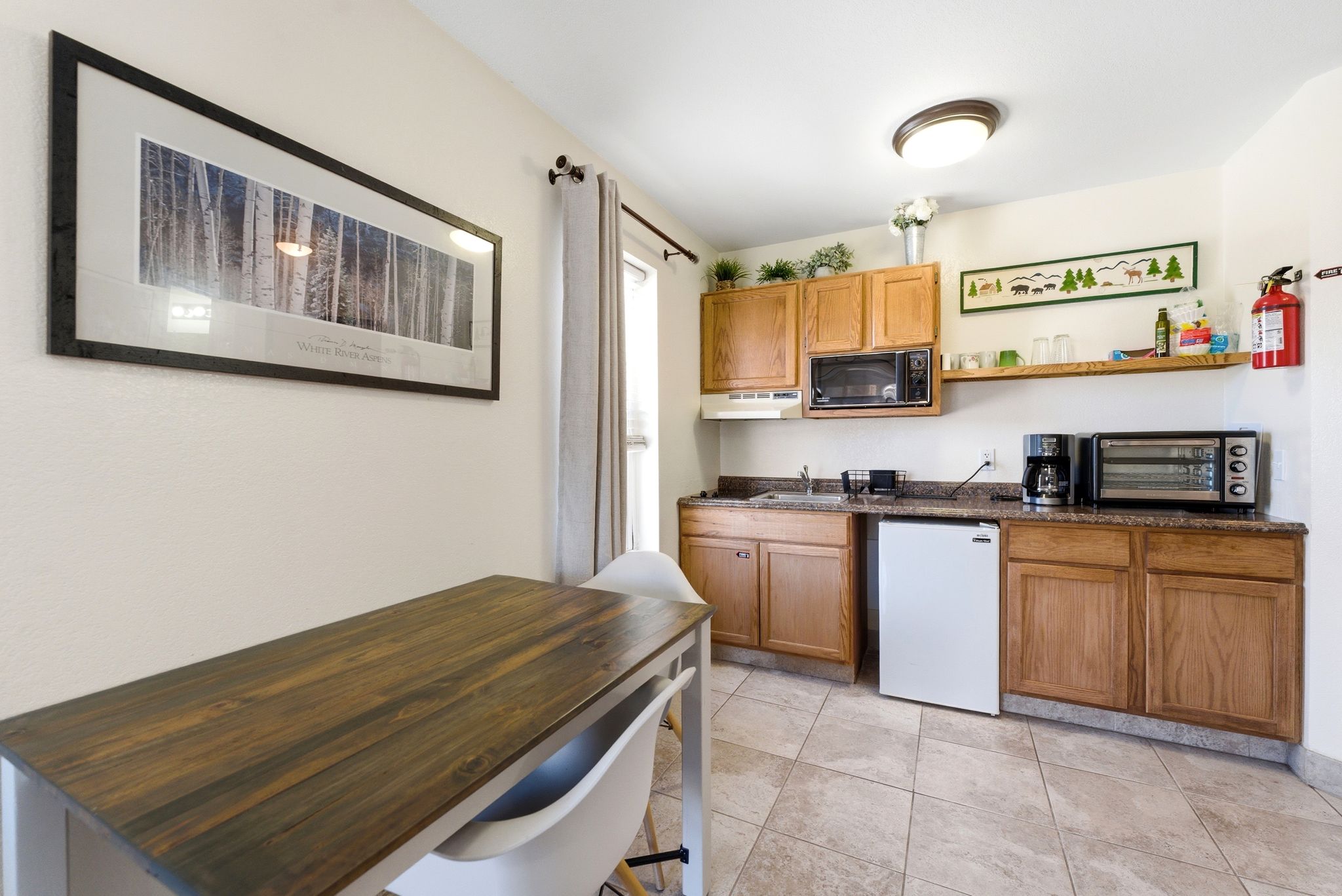 Compact kitchen area featuring wood cabinetry, stone-finish countertops, an under-counter refrigerator, and a built-in microwave