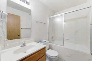 Bathroom featuring a wood-finish vanity with an integrated white sink, a chrome faucet, and a sliding glass shower door