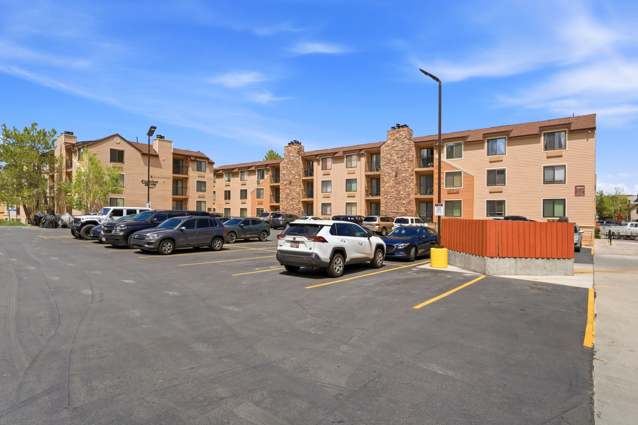 Multi-story residential buildings featuring tan siding, brown trim, and stone veneer accents