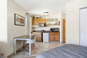 Efficient kitchen area featuring wood cabinetry, a microwave, and a compact refrigerator