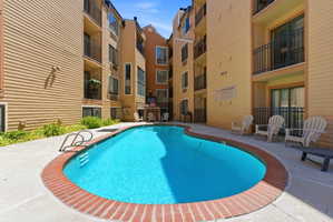 Curved swimming pool with a brick coping, surrounded by a concrete patio