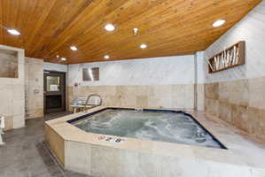 Indoor hot tub featuring a tile surround and blue tile interior