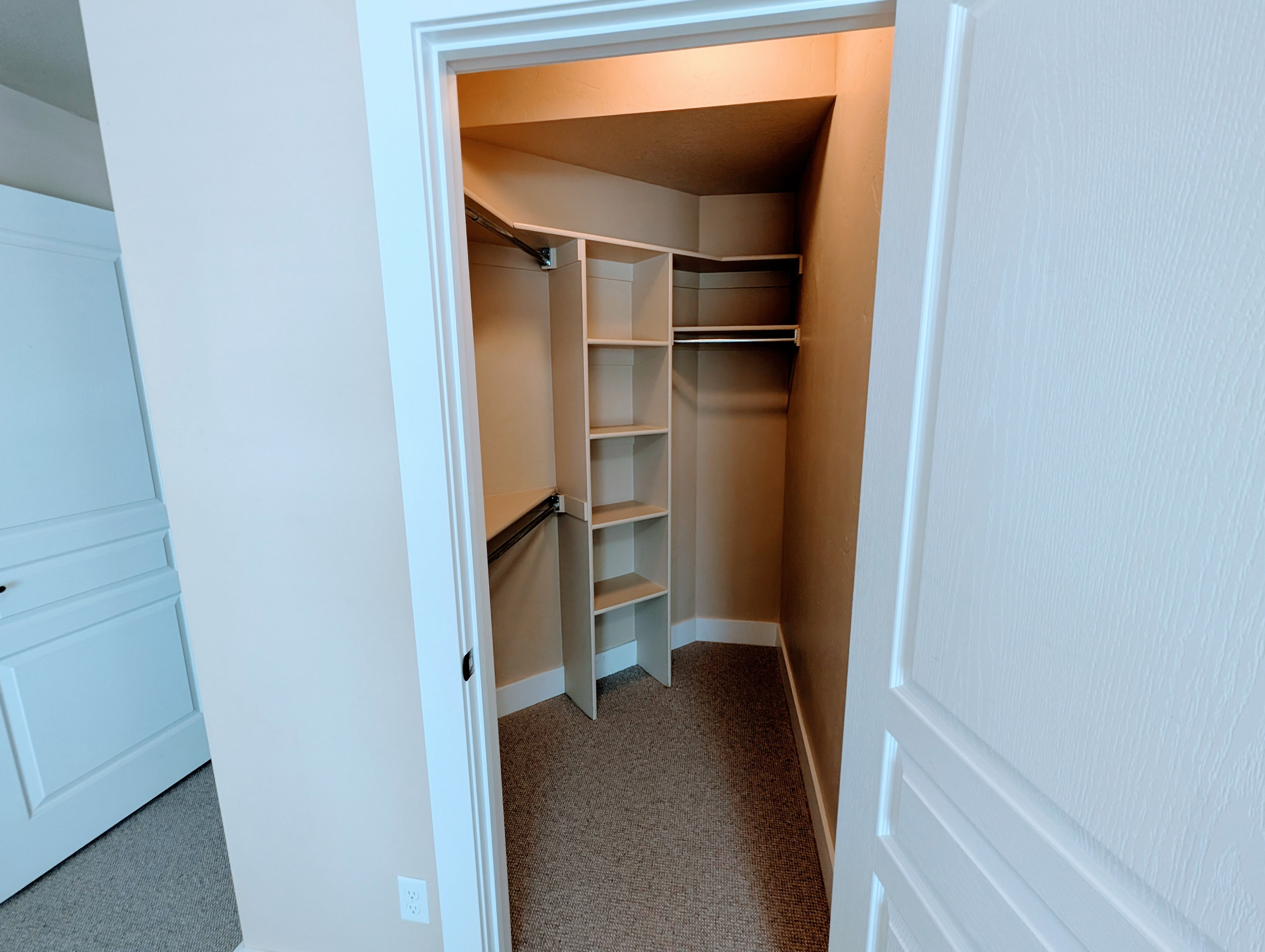 Walk-in closet featuring built-in shelving, multiple hanging rods, and neutral-toned carpeting
