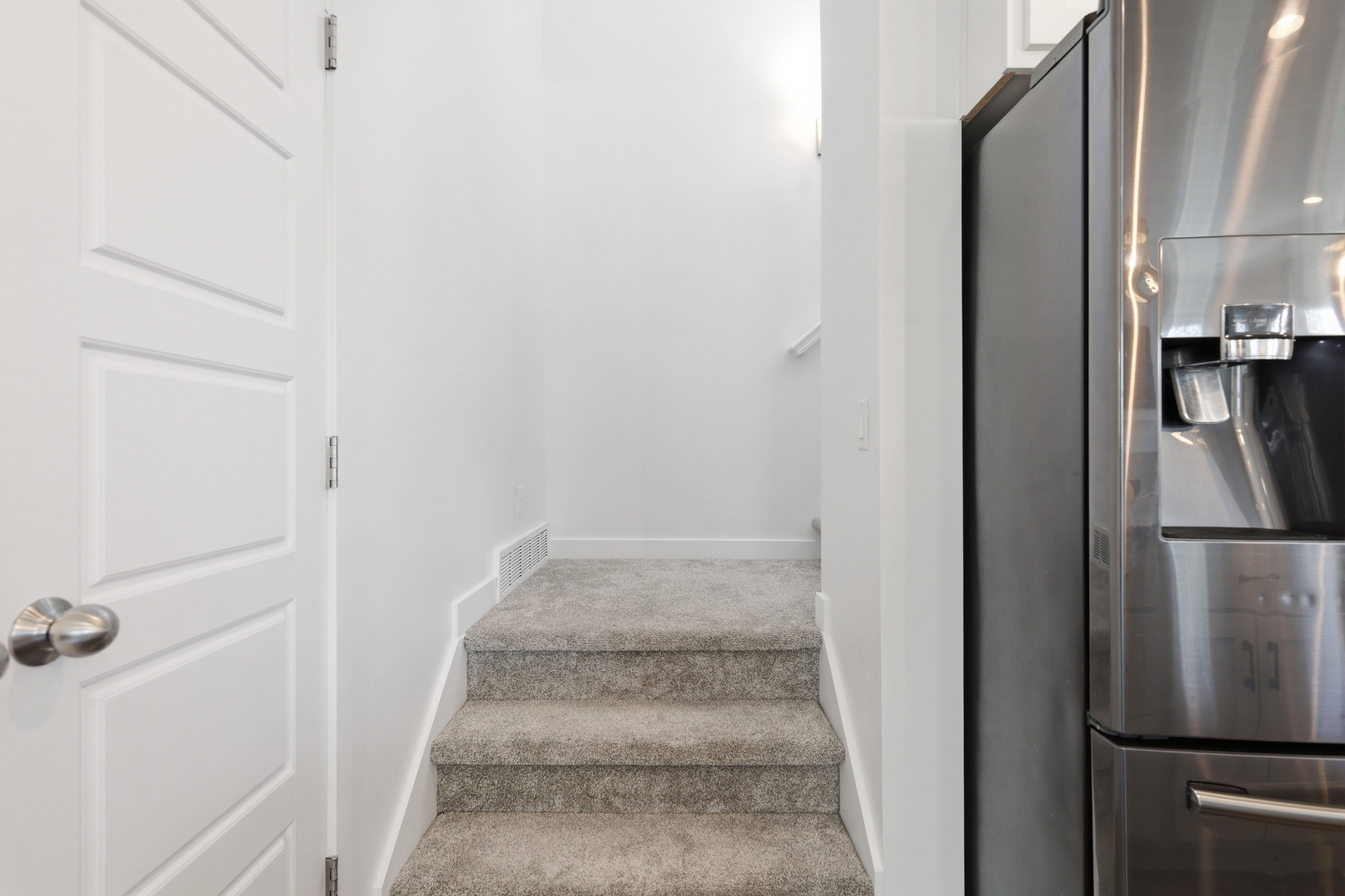 Carpeted staircase with white risers and white walls