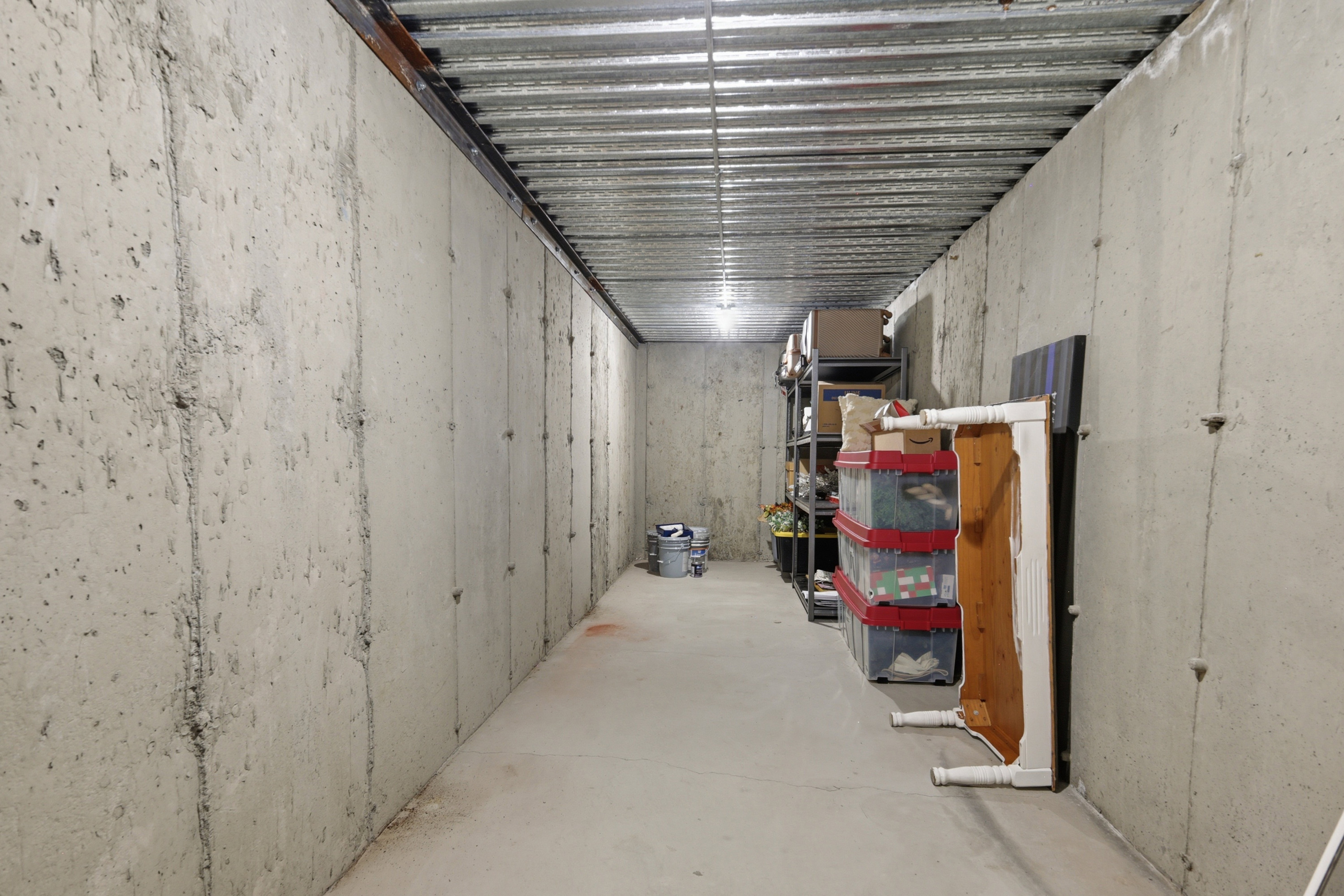 Basement space featuring concrete walls and a corrugated metal ceiling