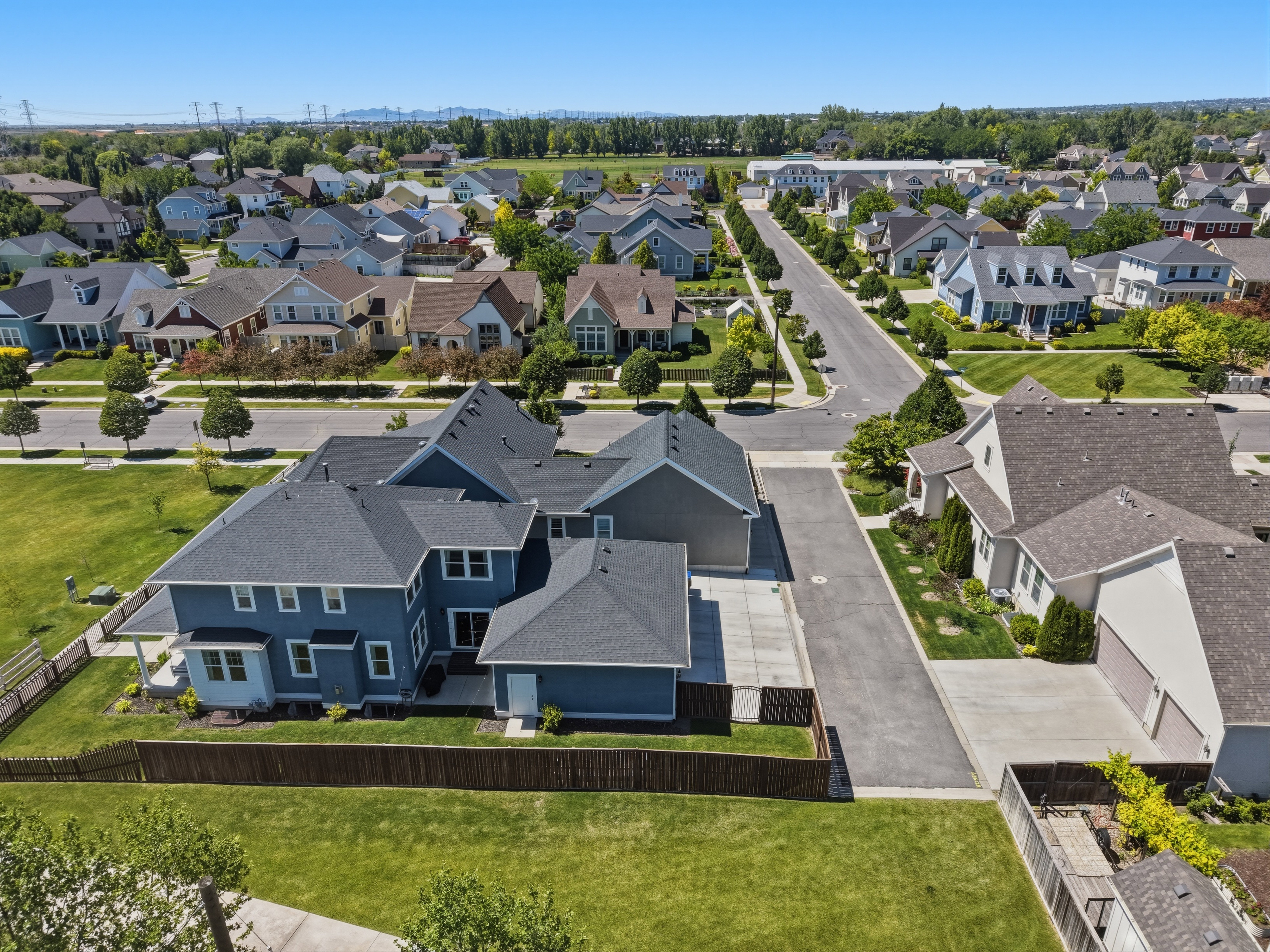 Expansive residential property featuring a blue exterior, dark shingle roof, attached garage, and a private rear yard with a wood fence