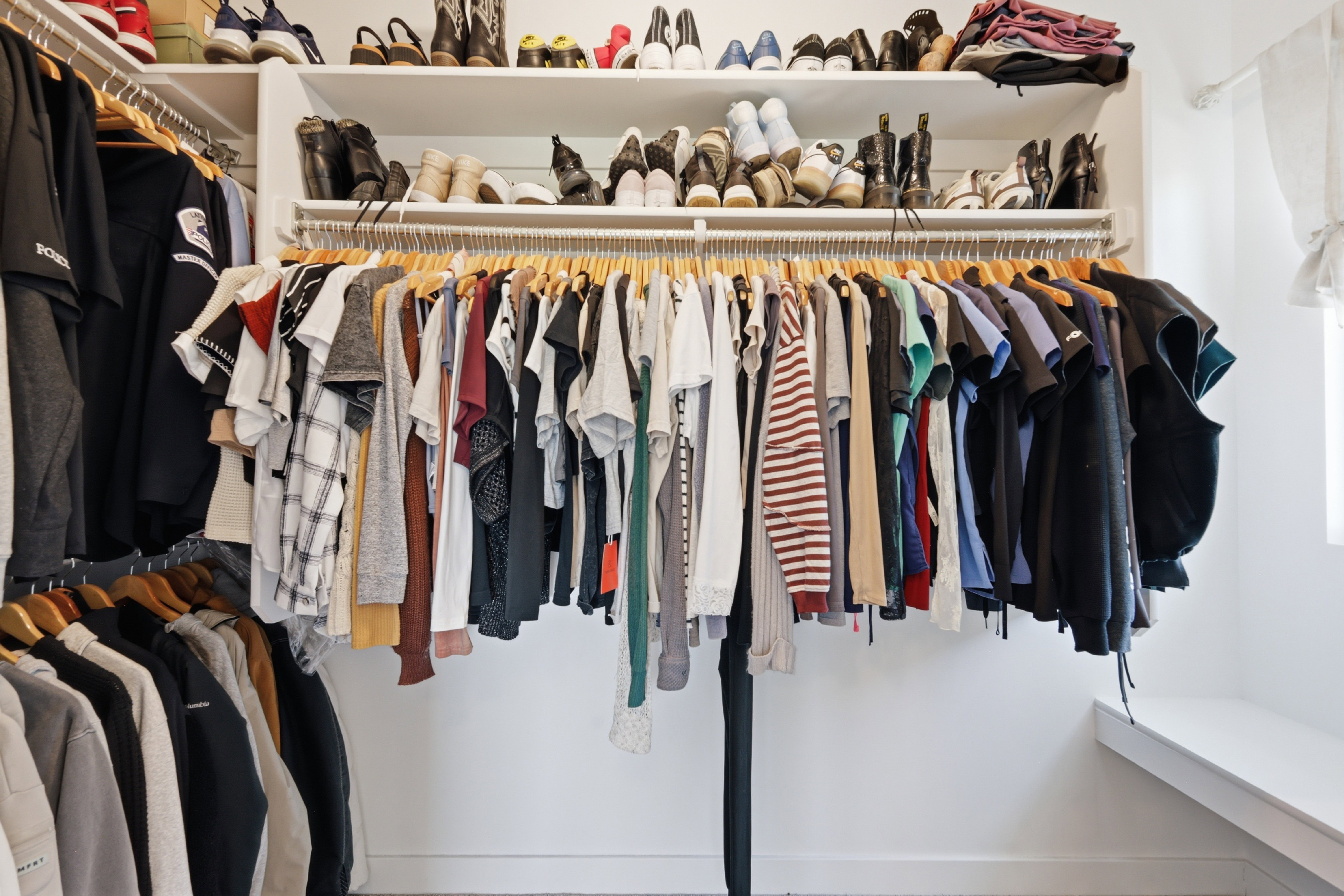 Custom closet system featuring multiple hanging rods, integrated shelving, and a built-in bench