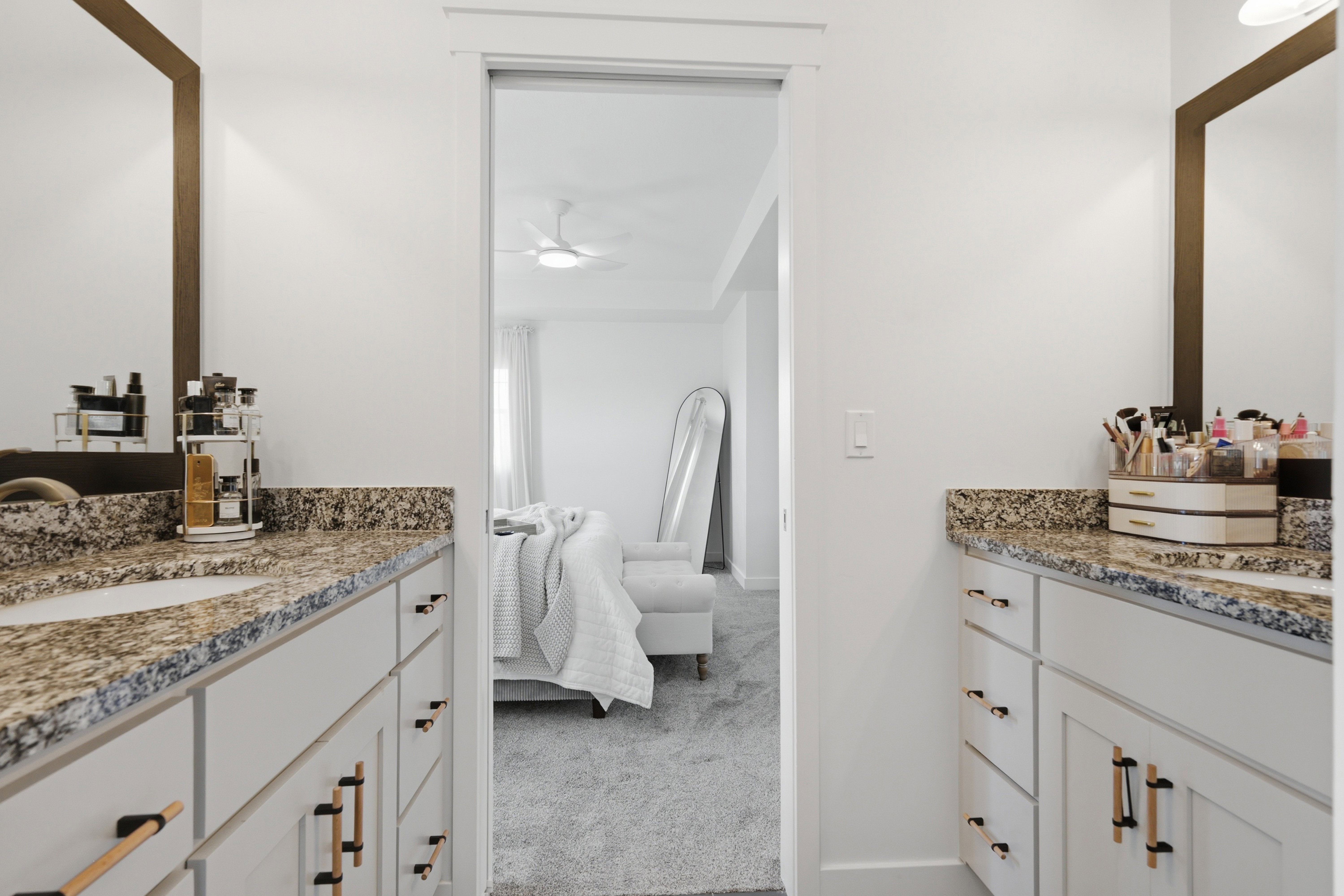 Dual vanity bathroom featuring light-toned cabinetry with modern hardware, granite countertops, and individual undermount sinks