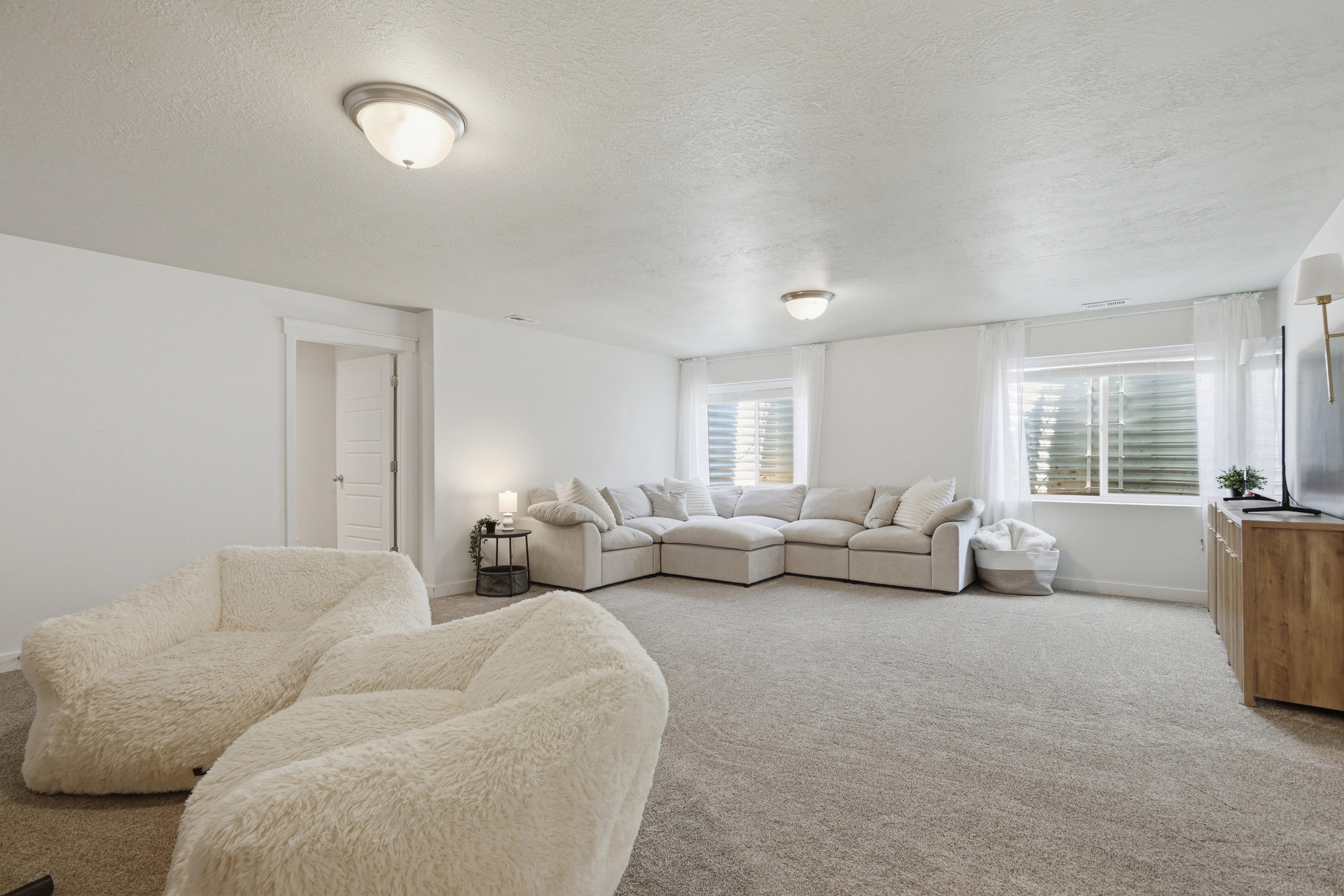 Spacious room featuring light-colored carpeting, white walls, and two ceiling-mounted dome light fixtures