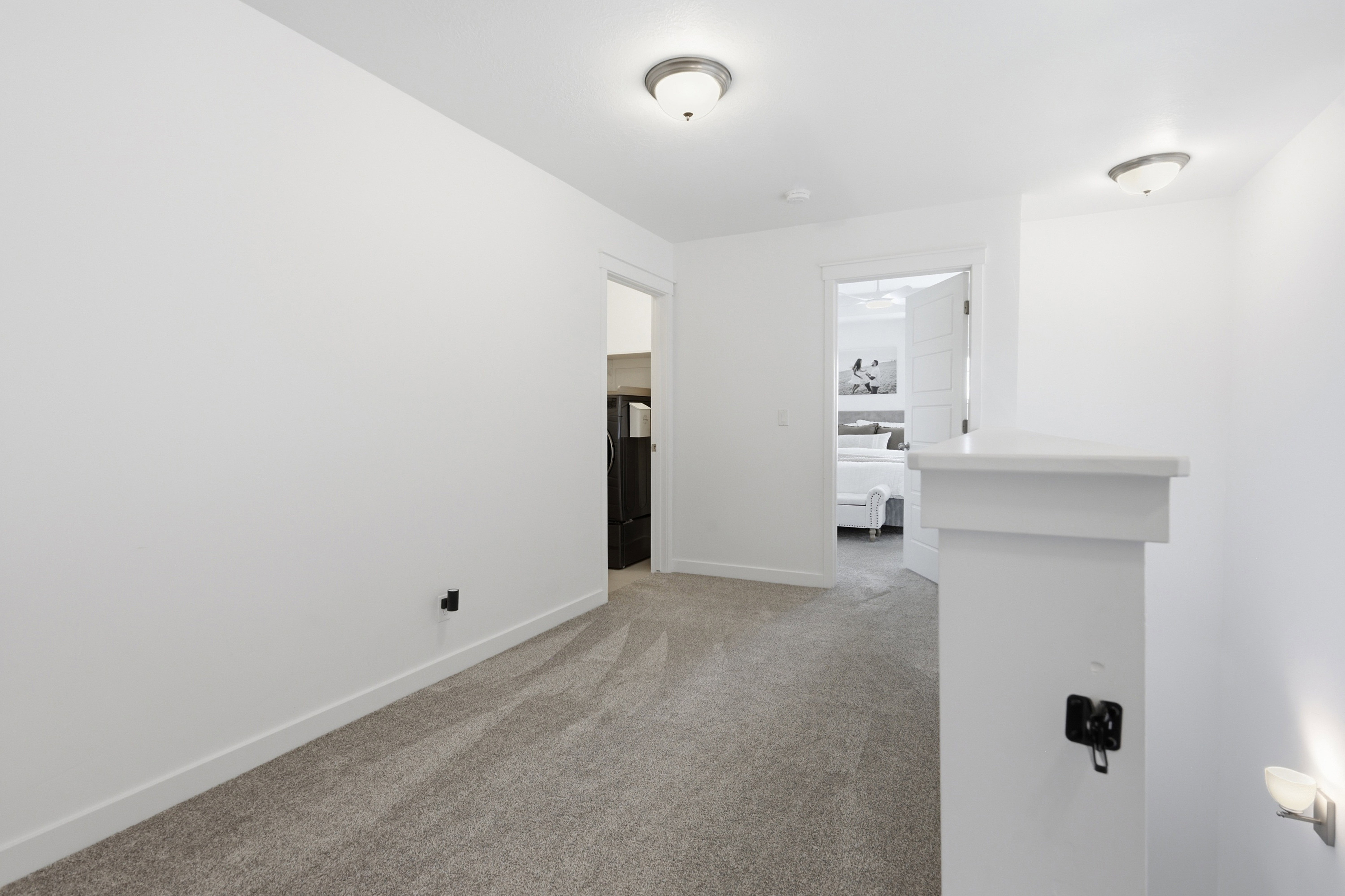 Carpeted hallway featuring white walls, white trim, and two semi-flush mount ceiling lights