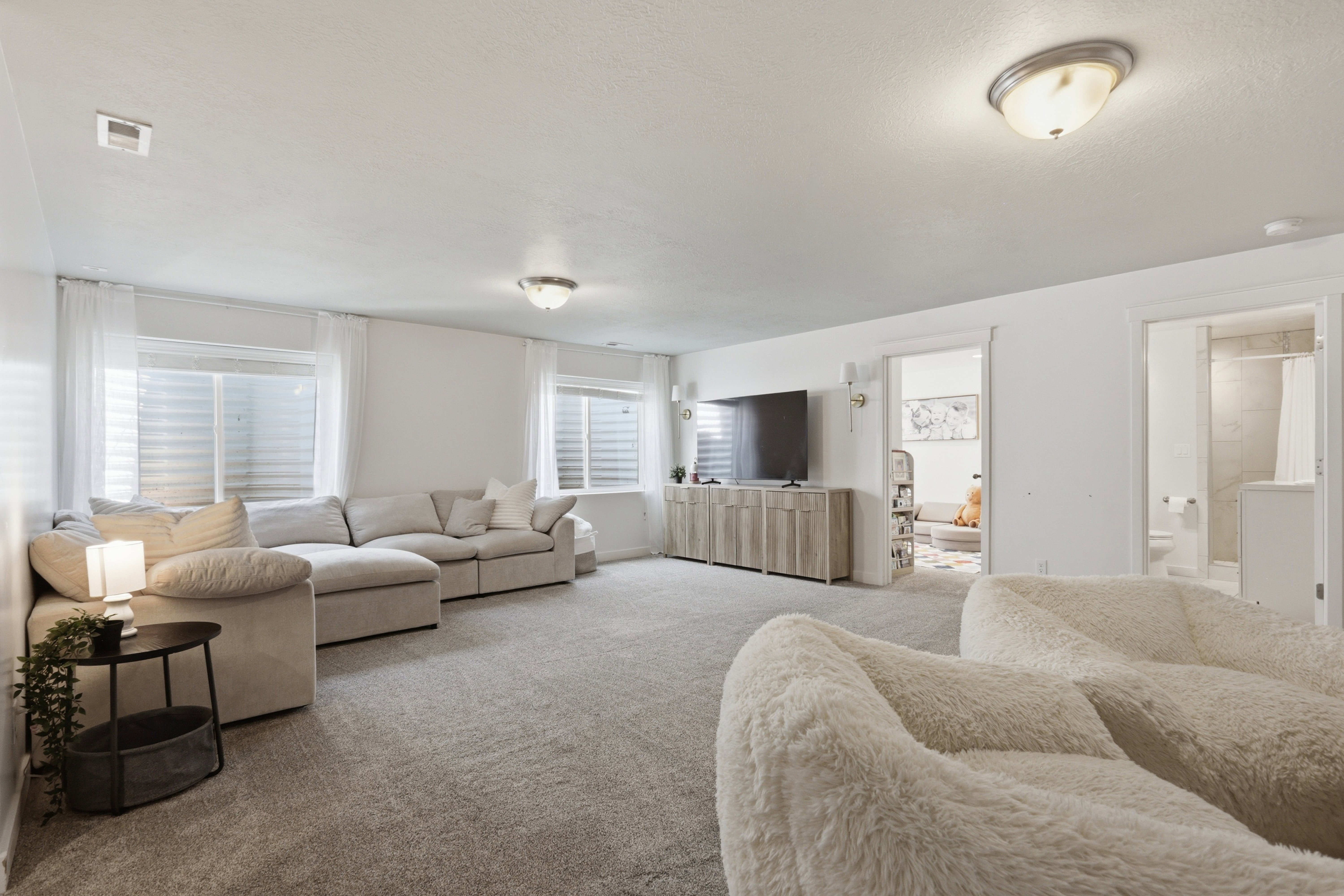 Spacious lower-level living area with light gray carpet flooring