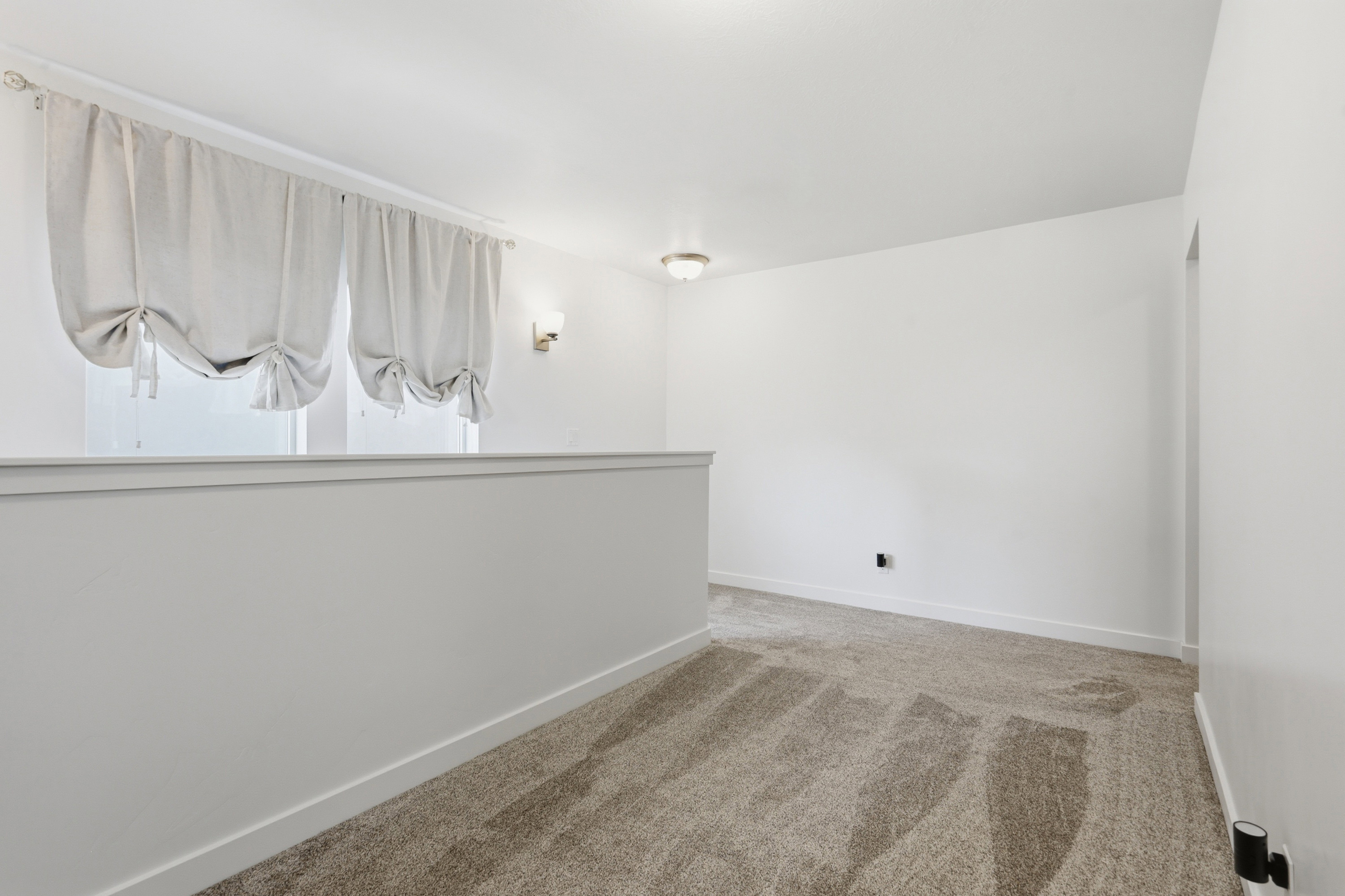 Loft area featuring neutral carpeting, white walls, and a low half-wall partition
