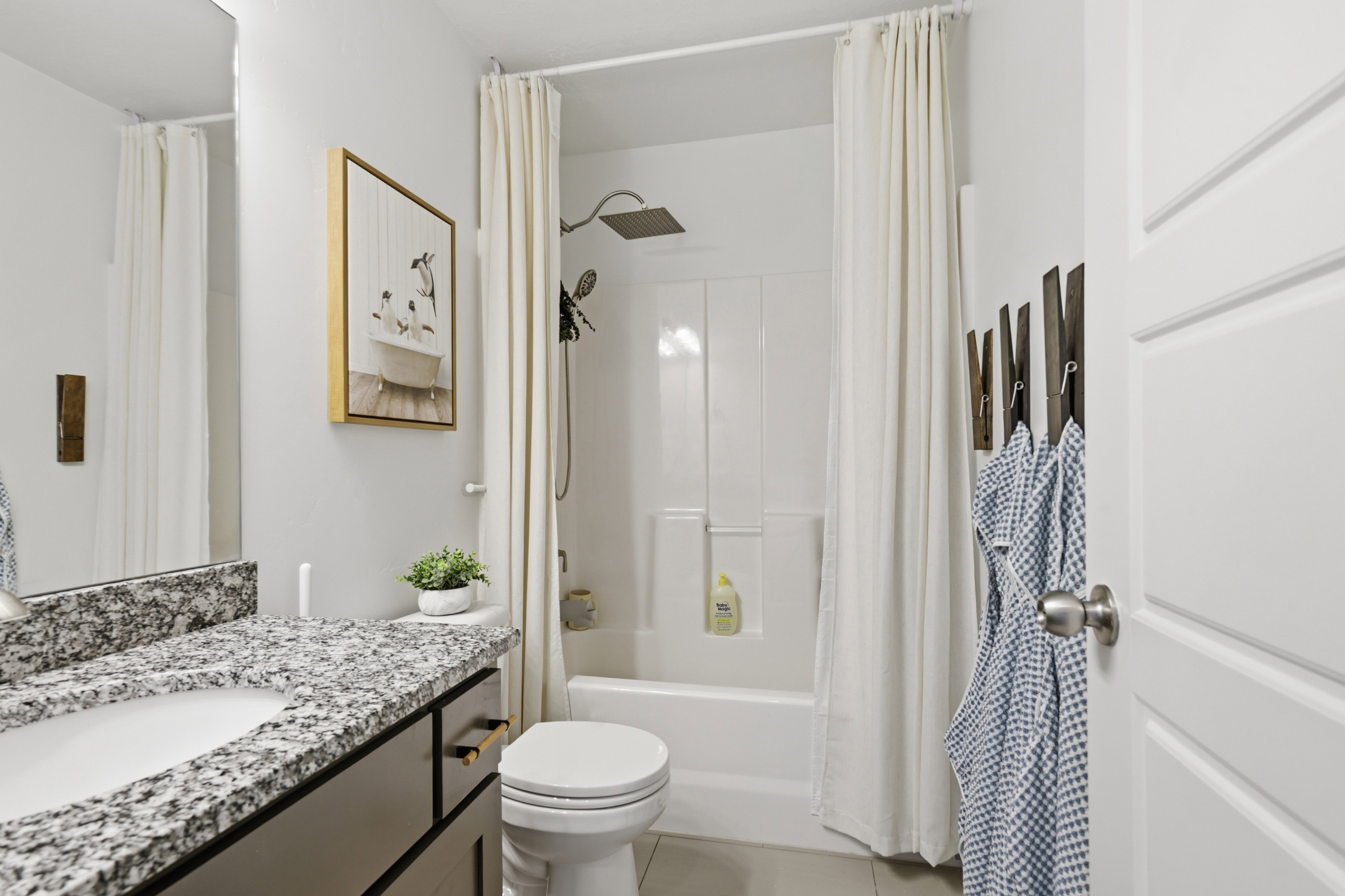 Bathroom featuring a white shower-over-tub combination with a rain showerhead, a single vanity with a granite-style countertop and integrated sink, a built-in medicine cabinet, and a panel door