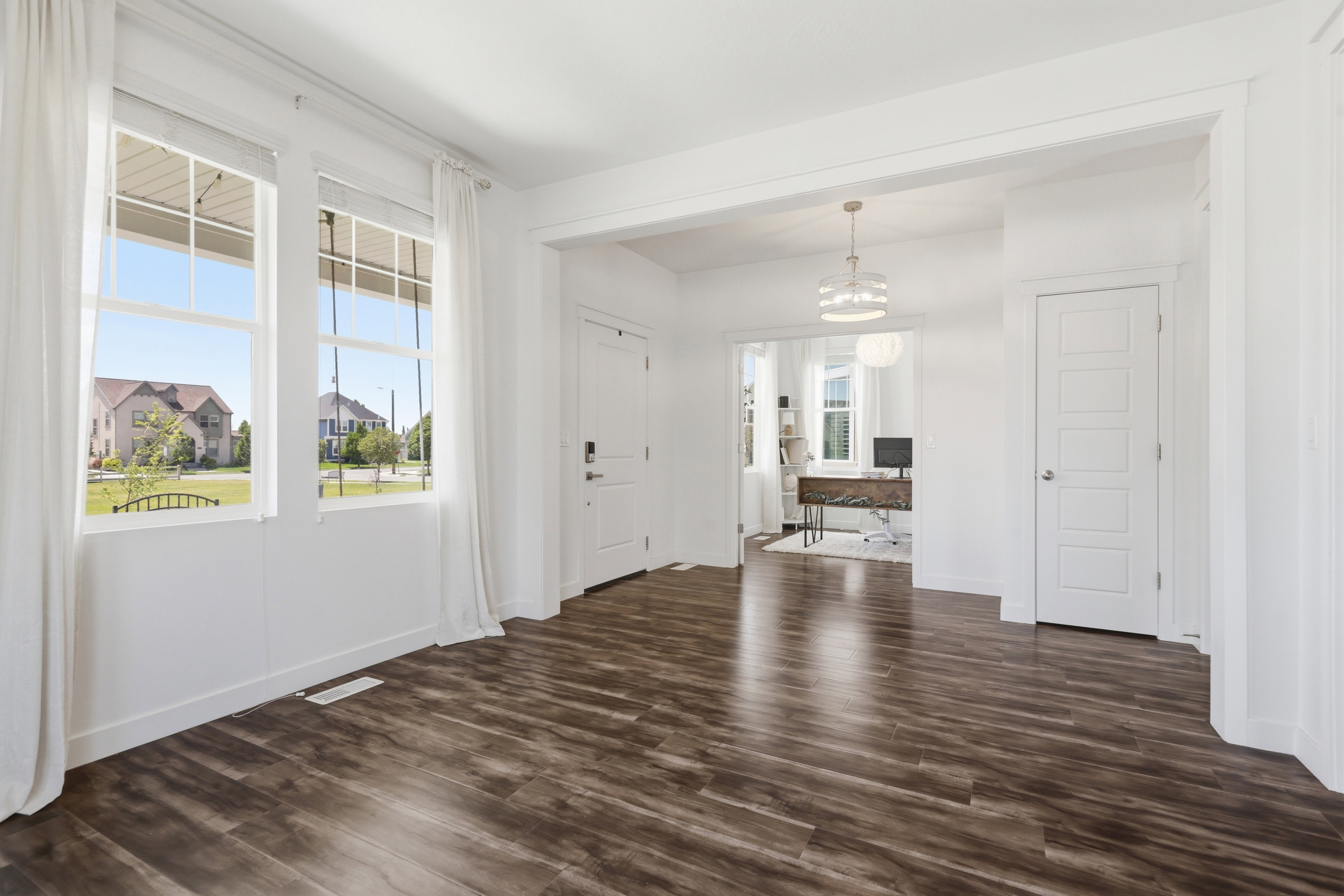Spacious interior featuring wood-finish flooring, white walls, and multiple windows