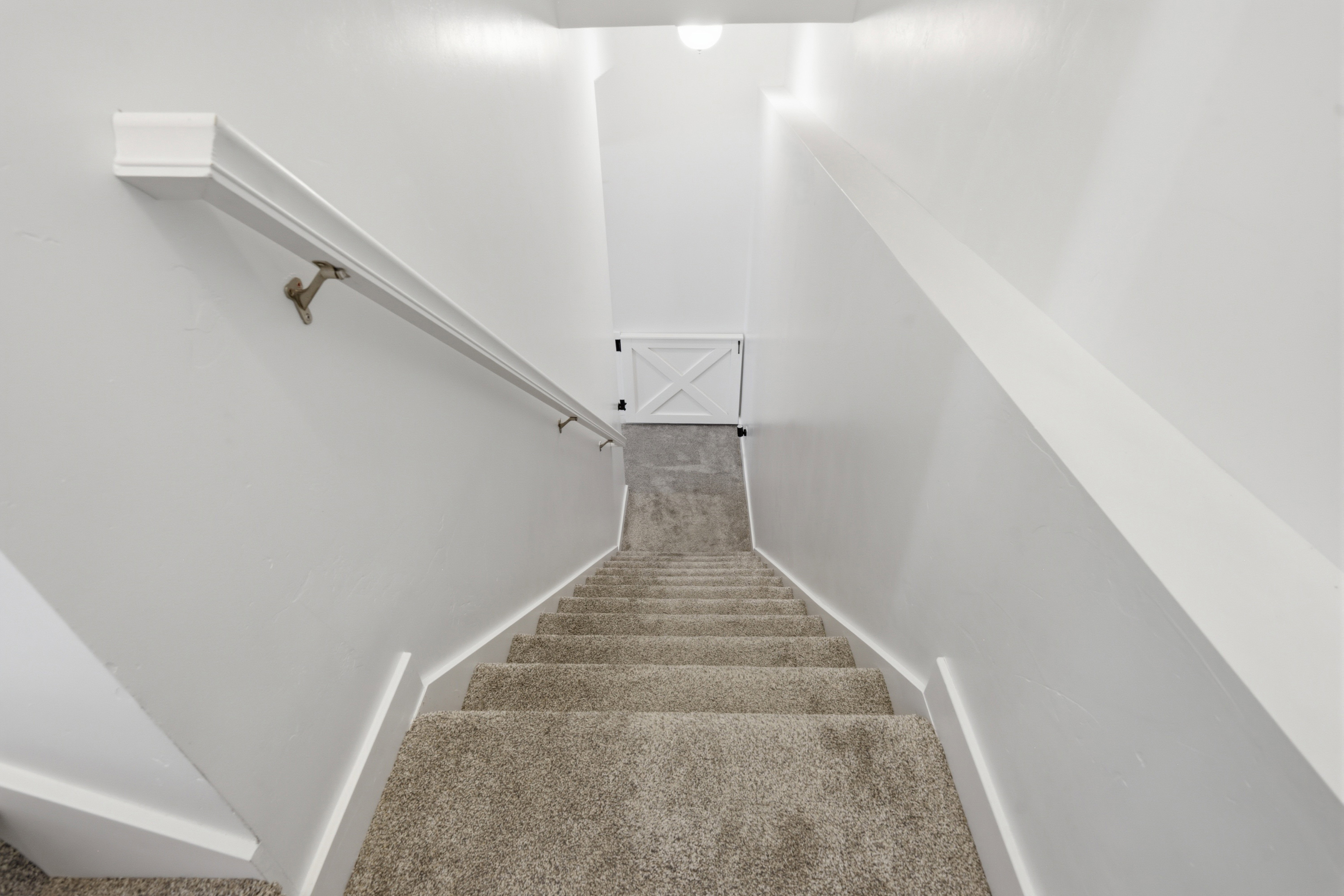 Carpeted staircase with white painted walls and a classic white handrail