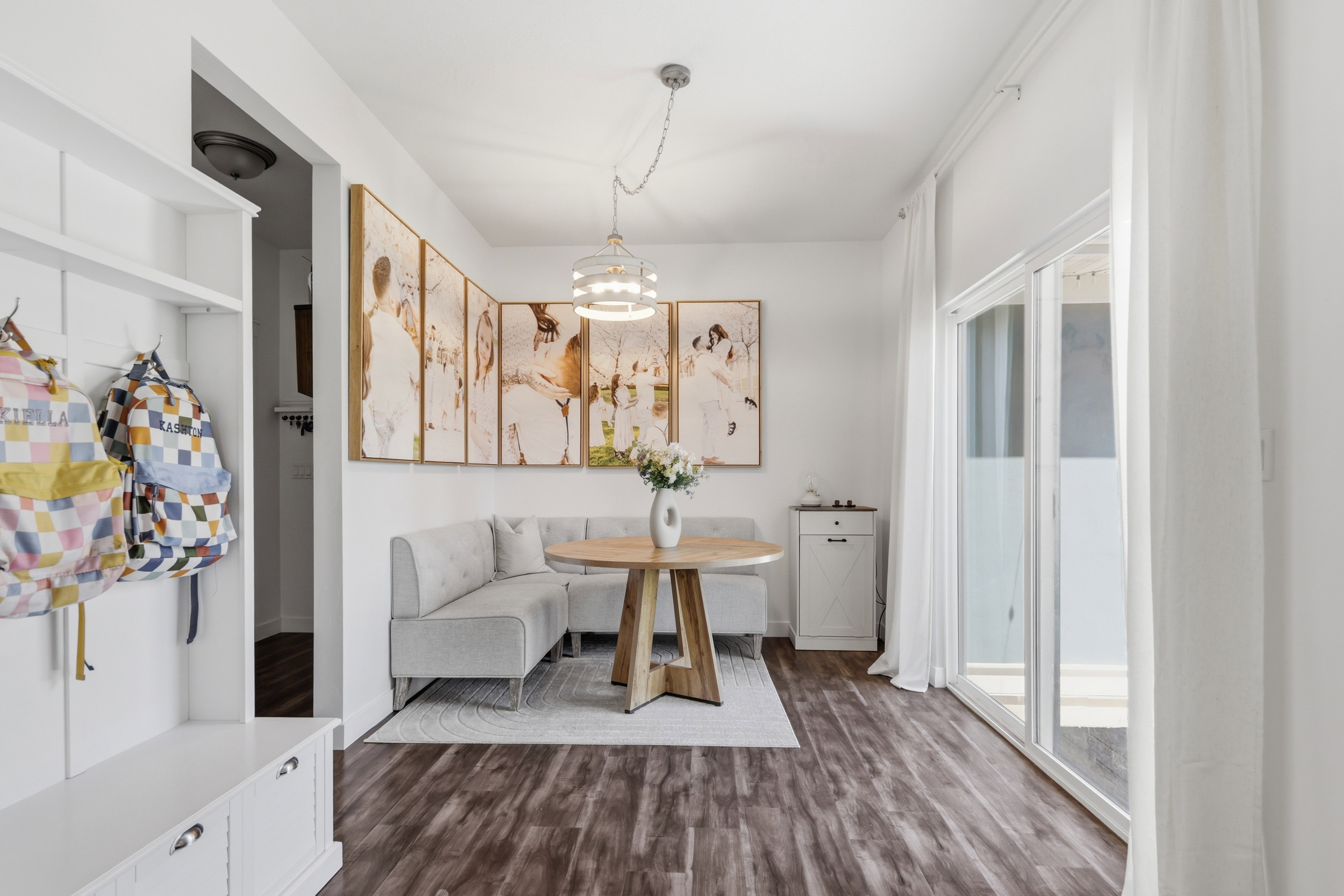 Bright dining area featuring wood-finish flooring, a built-in banquette, and a linear chandelier
