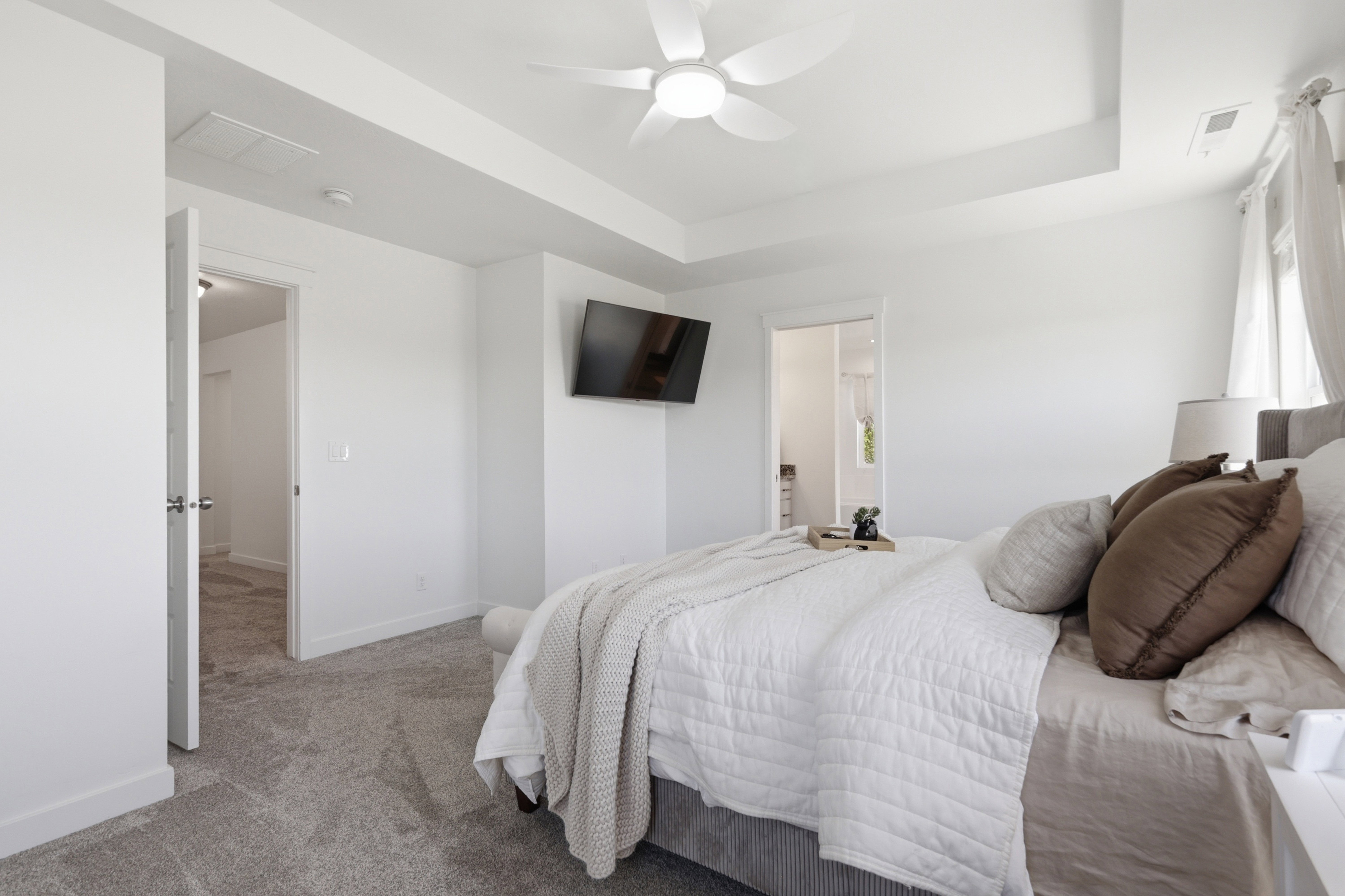 Carpeted bedroom featuring a tray ceiling, ceiling fan, and white walls