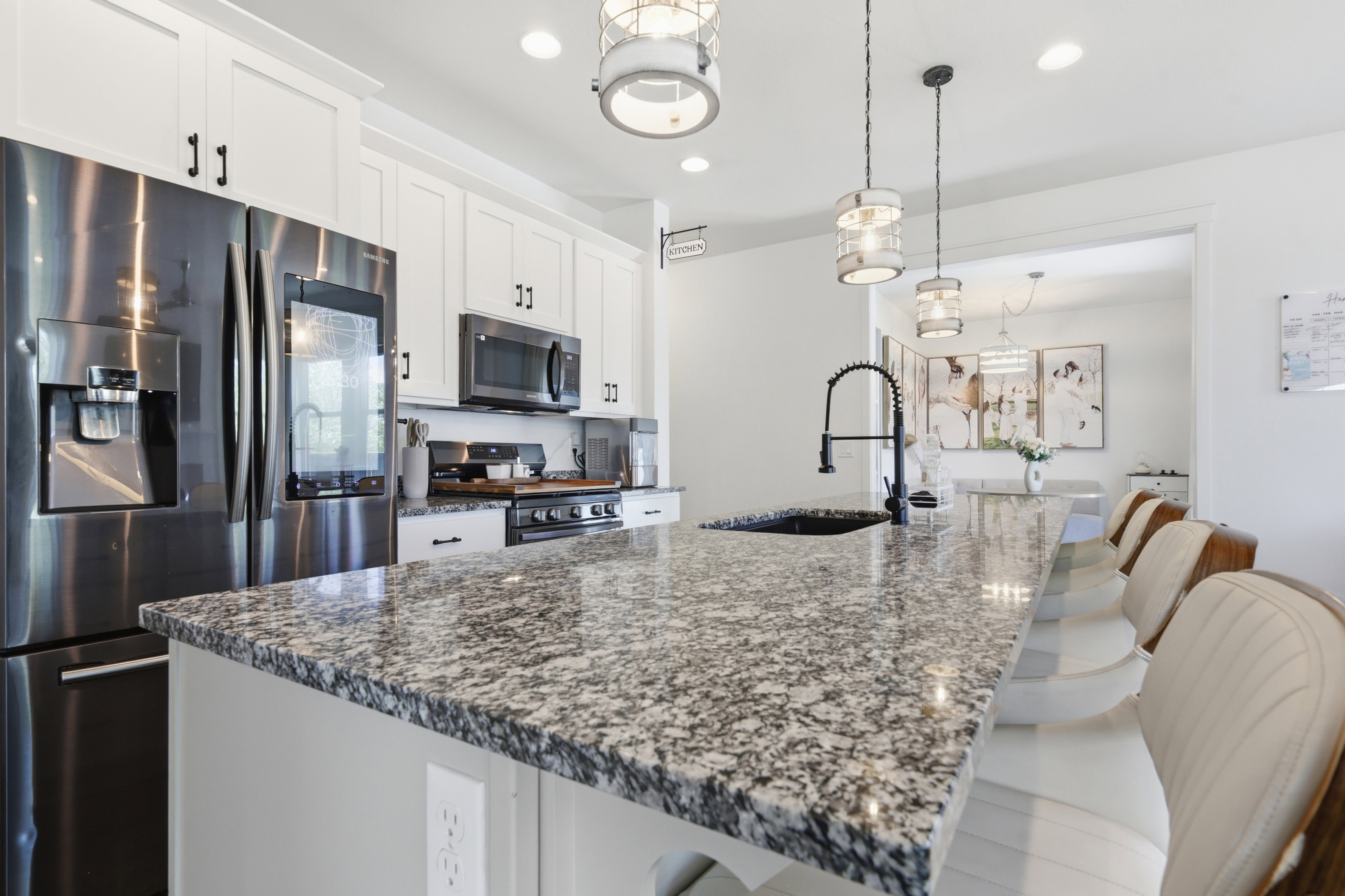 Kitchen island featuring a speckled countertop, integrated sink with a black gooseneck faucet, and overhead pendant lighting