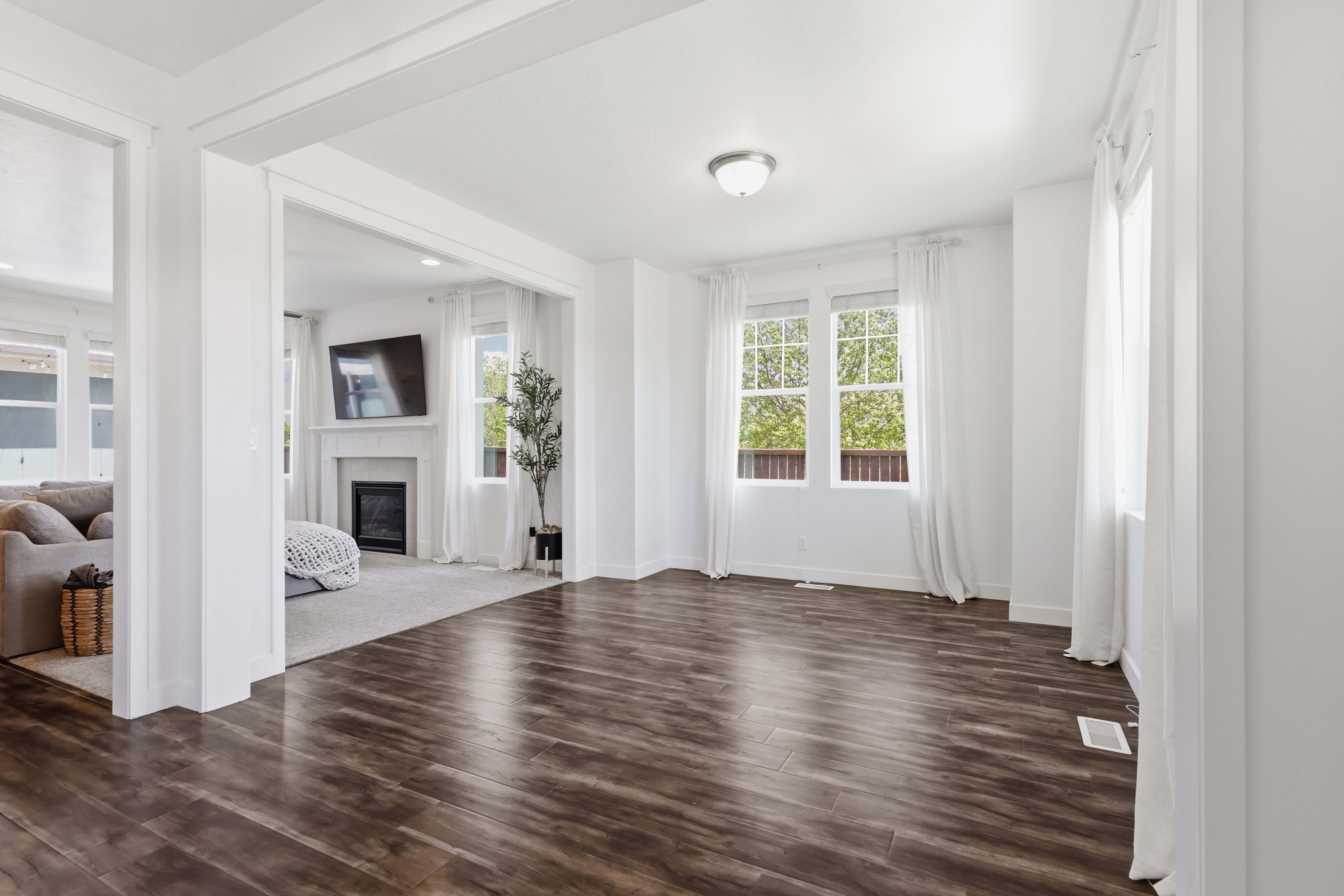 Spacious room featuring wood-finish flooring, white walls, and multiple windows