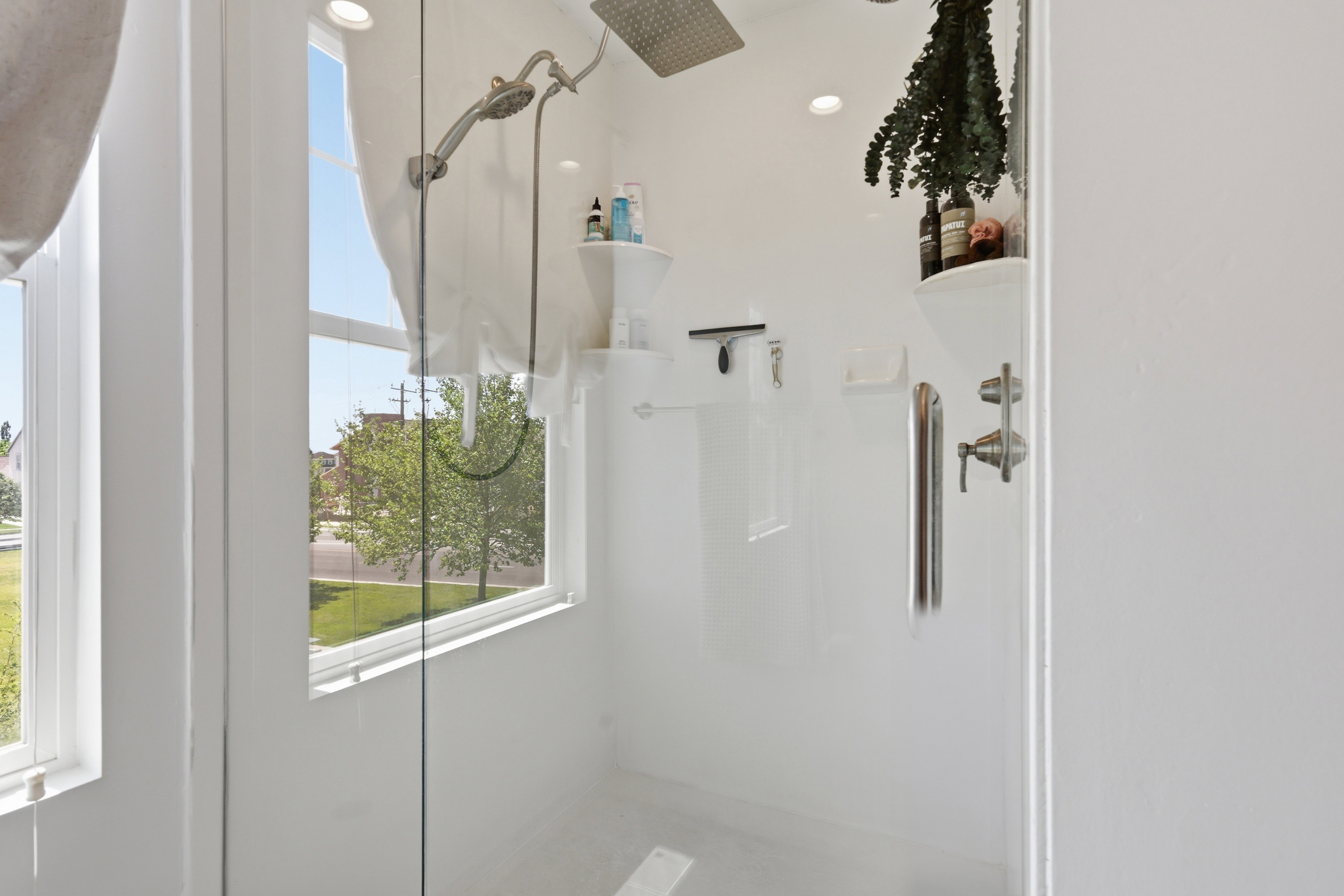 Modern shower enclosure featuring clear glass panels, a ceiling-mounted rainfall showerhead, and an additional handheld shower fixture