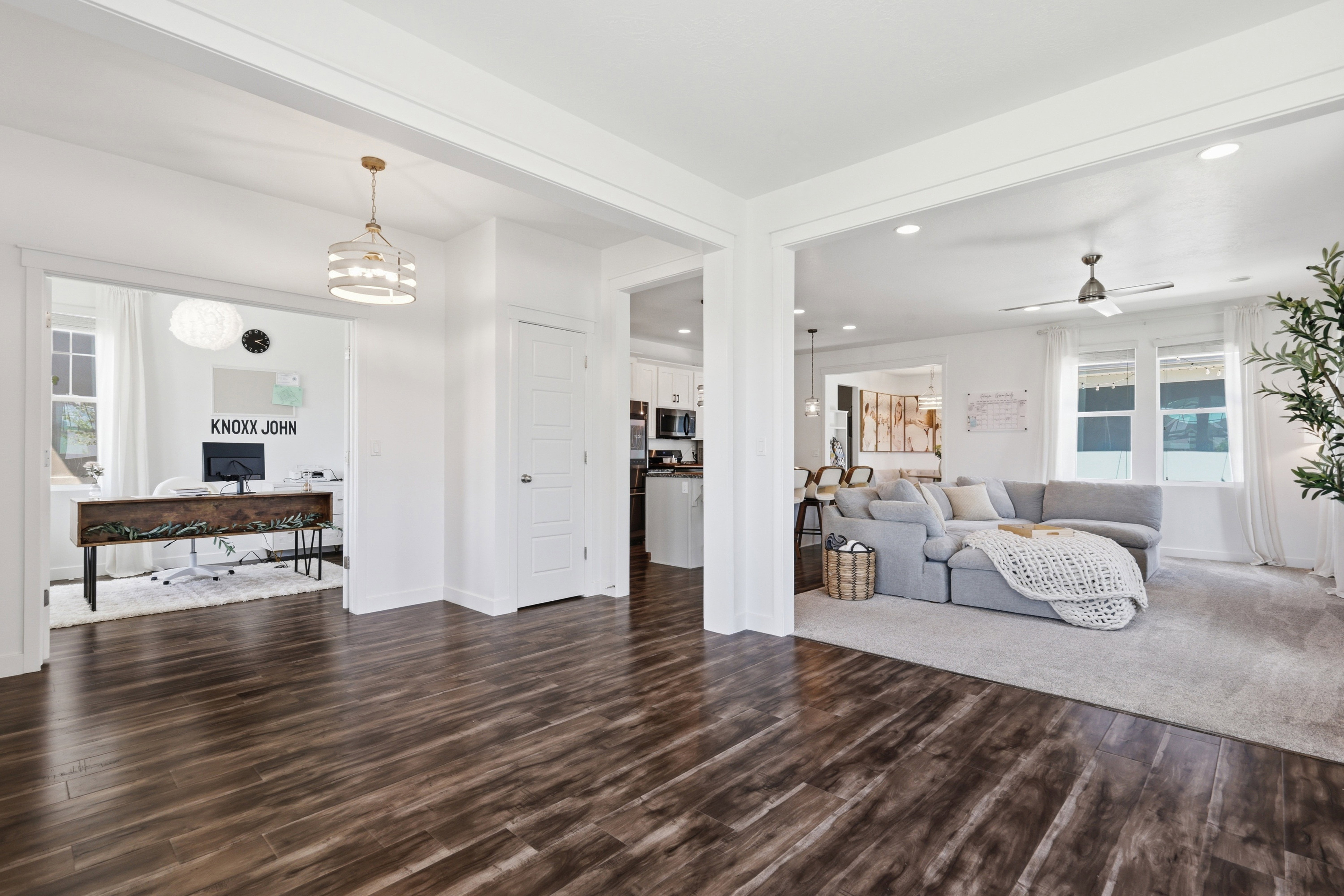 Open concept living space featuring dark wood-finish flooring, white walls, and bright recessed lighting