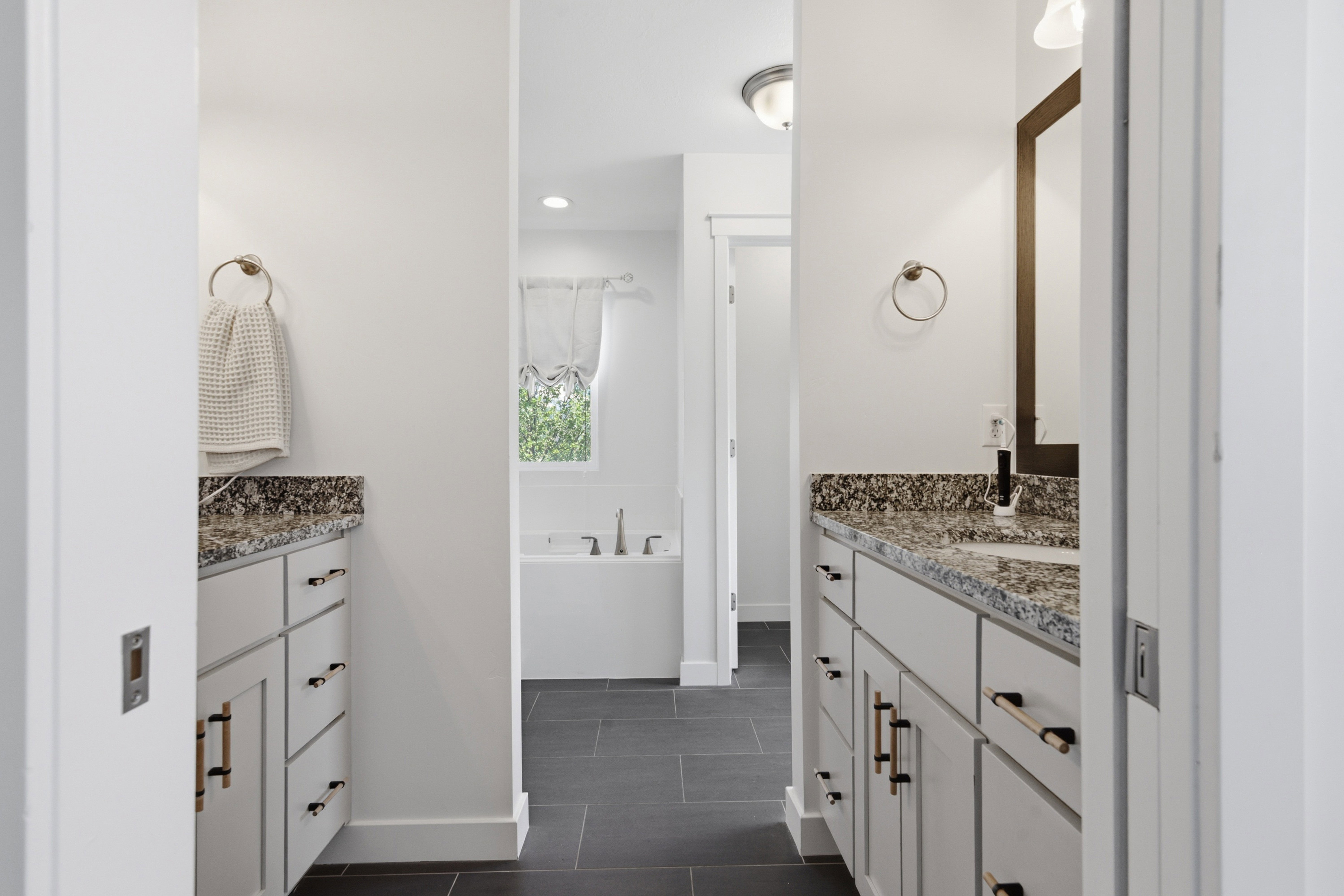 Dual vanity sinks with granite countertops and white cabinetry