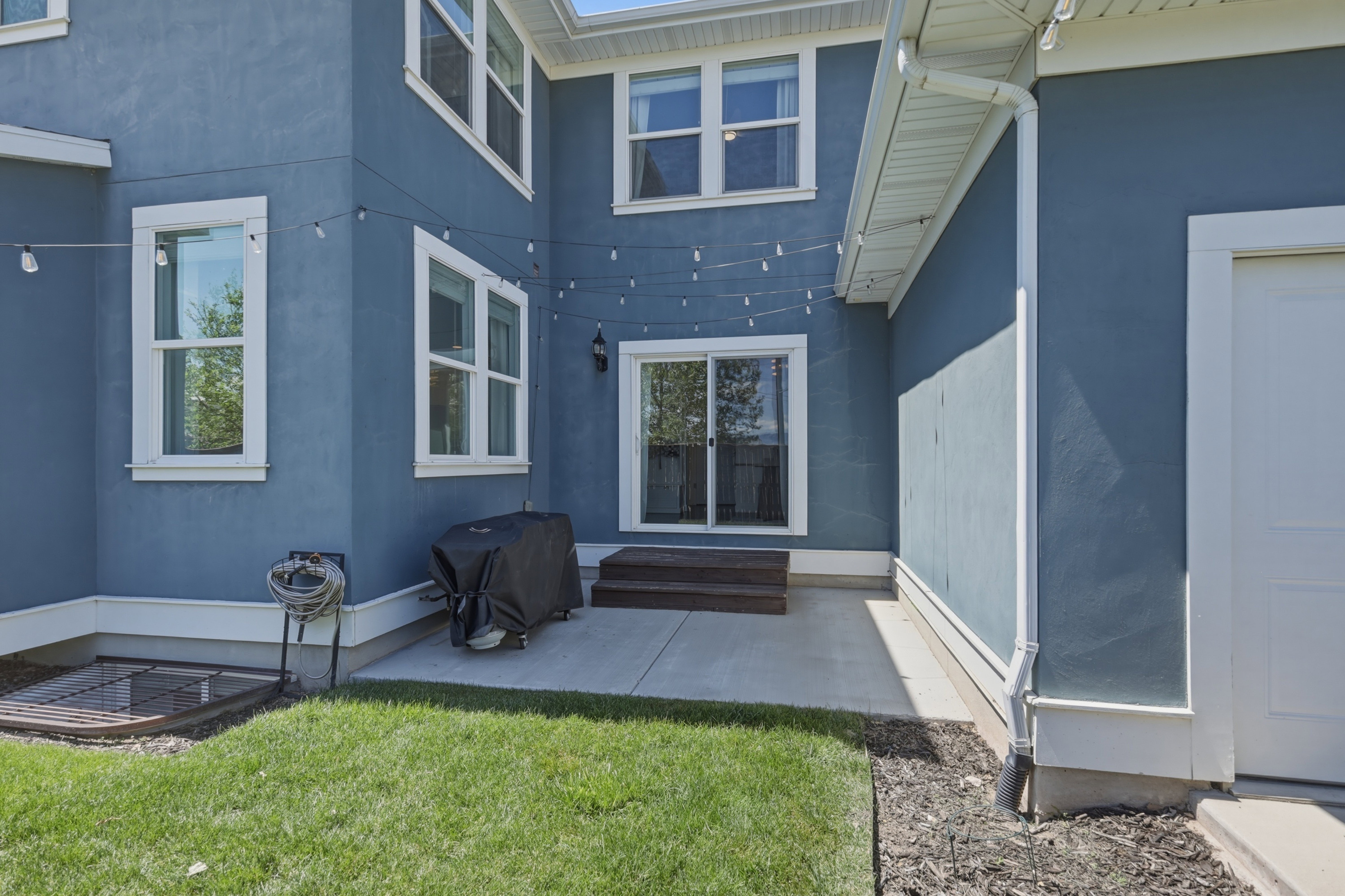 Exterior stucco siding in a deep blue tone, featuring multiple white-trimmed windows and a sliding glass door